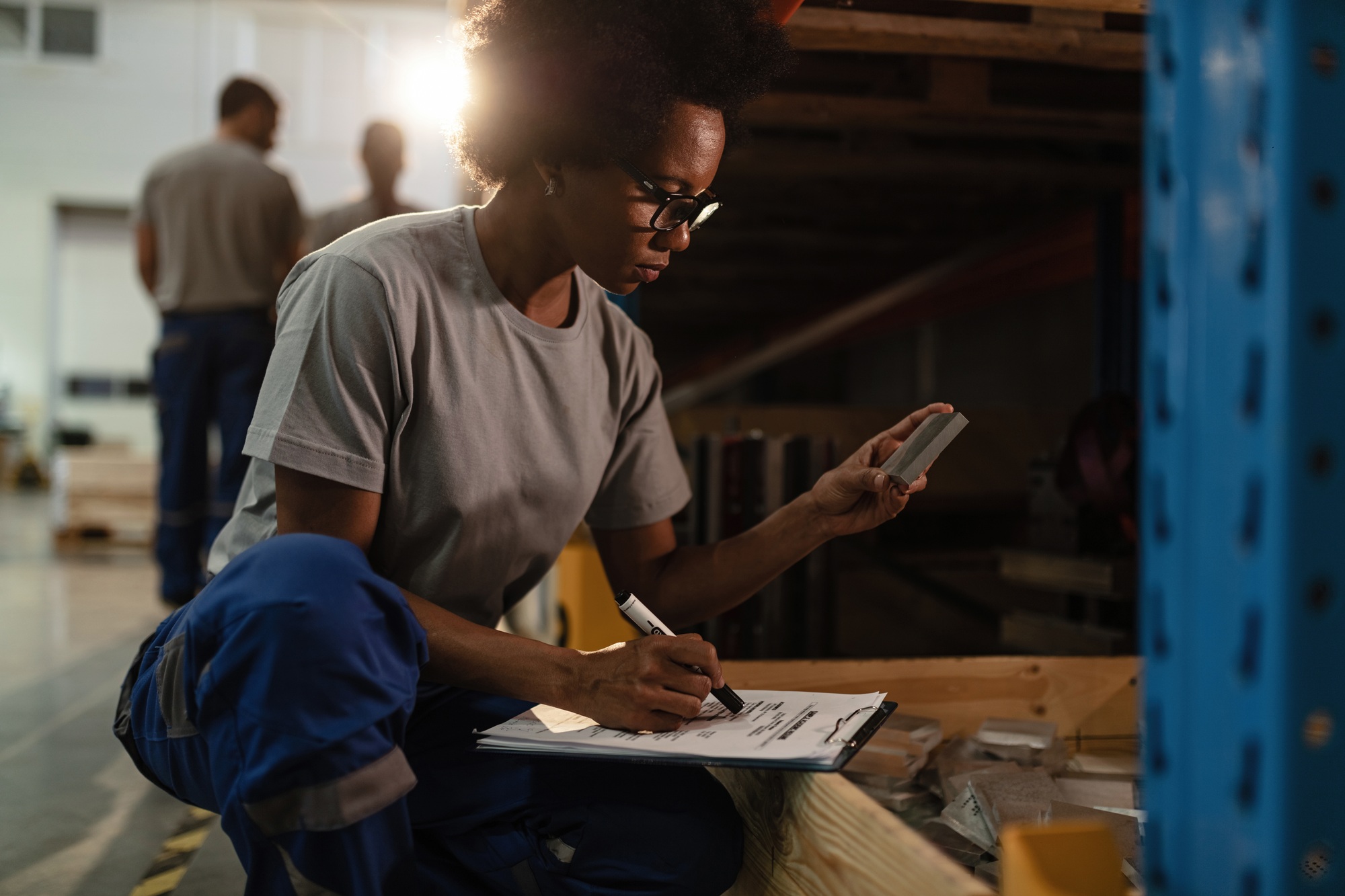 African American warehouse worker making a record of products in shipment list.