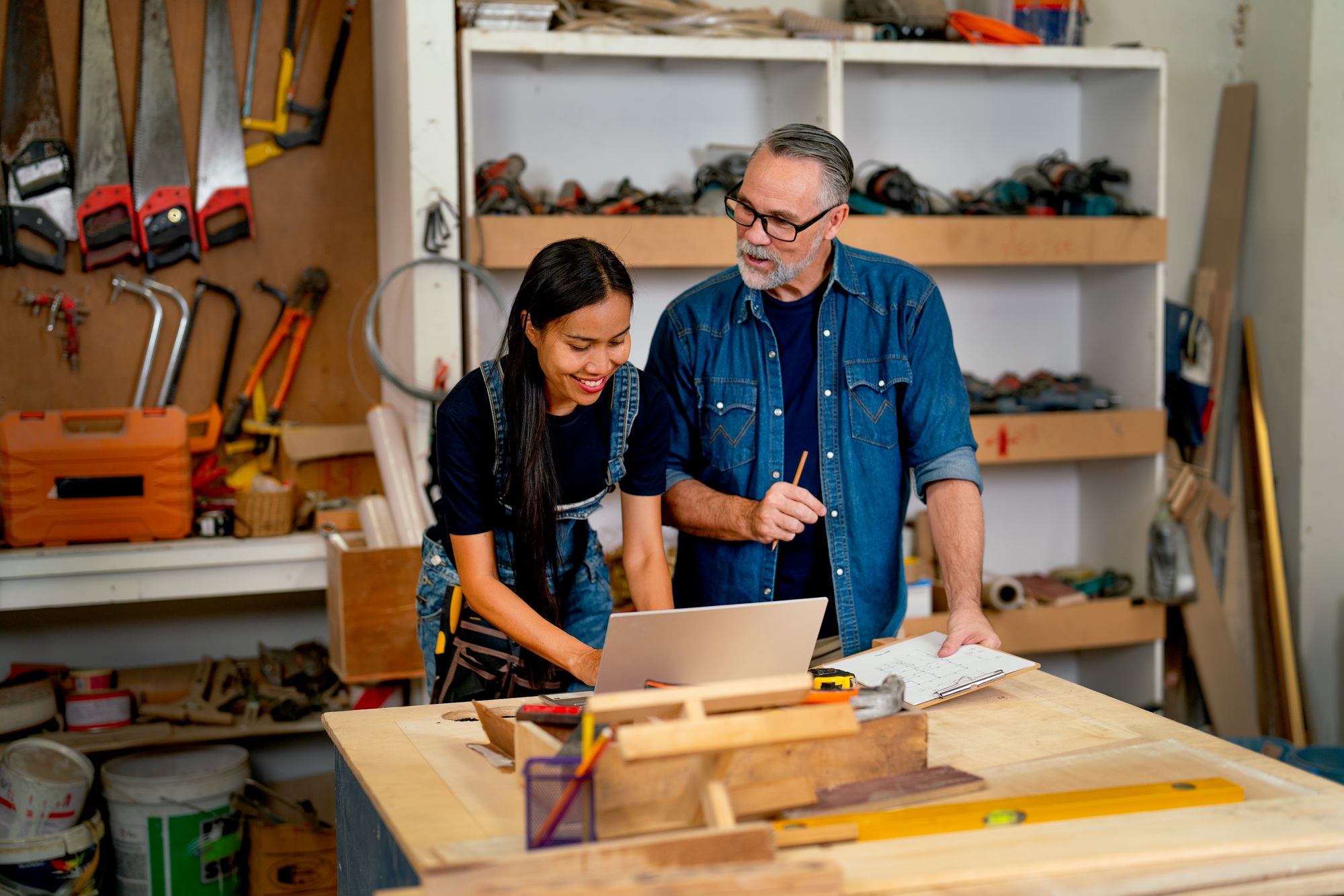 Asian wood worker woman use laptop to check detail of order from customer and discuss together