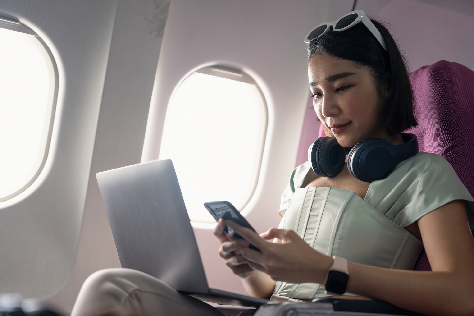 Attractive asian woman passenger of airplane read news from networks via smartphone and wifi on