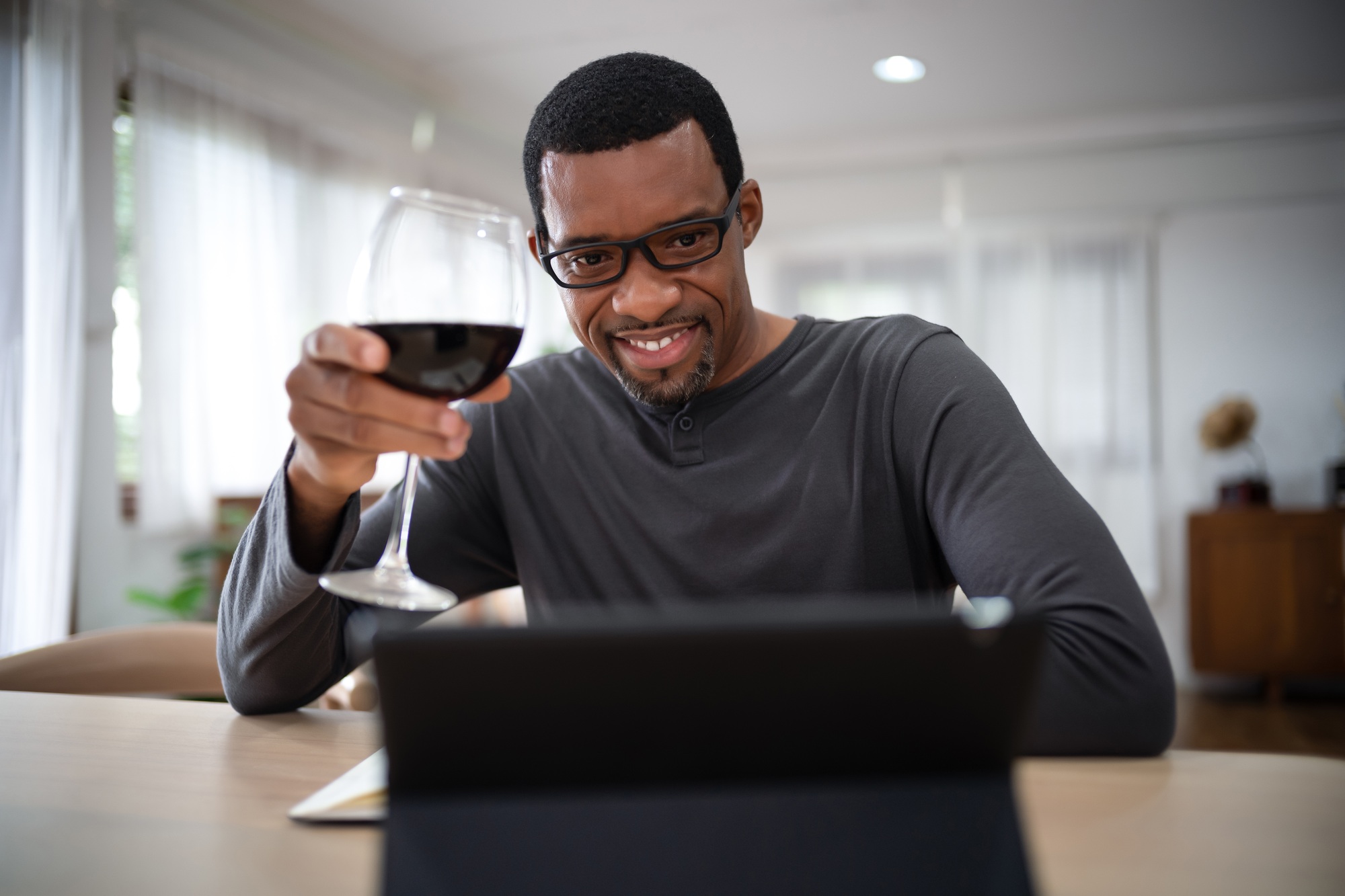 Black bearded man drinking win talking meeting on video call celebrate party in living room