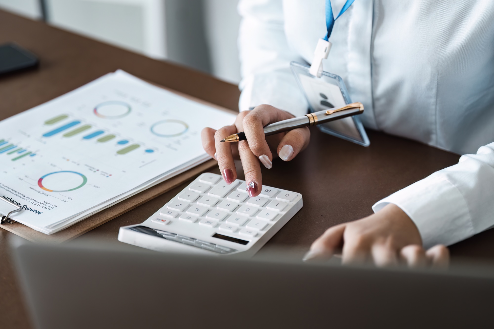 Business Professional Analyzing Financial Data with Calculator and Charts in Office Setting