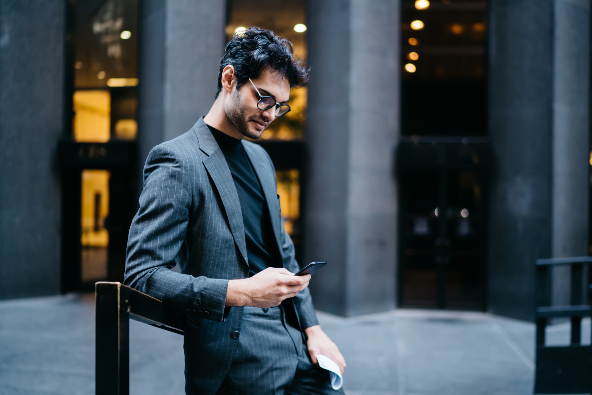 businessman in trendy eyewear searching sms message on mobile gadget