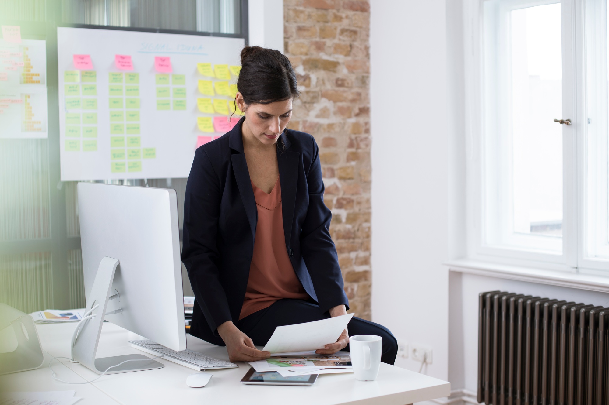 Businesswoman at desk in office looking at printouts