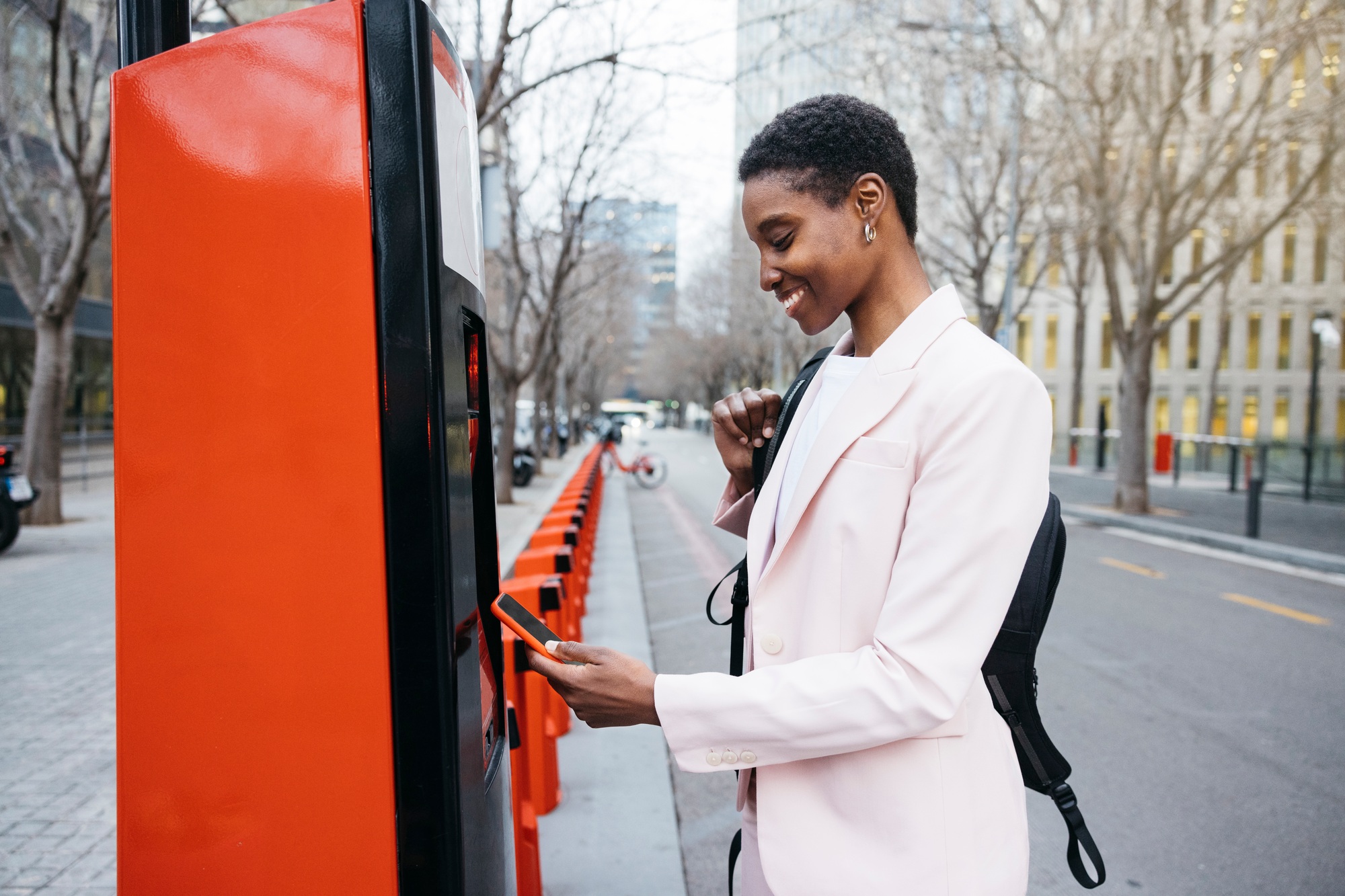 Businesswoman using mobile app to rent a city bike.