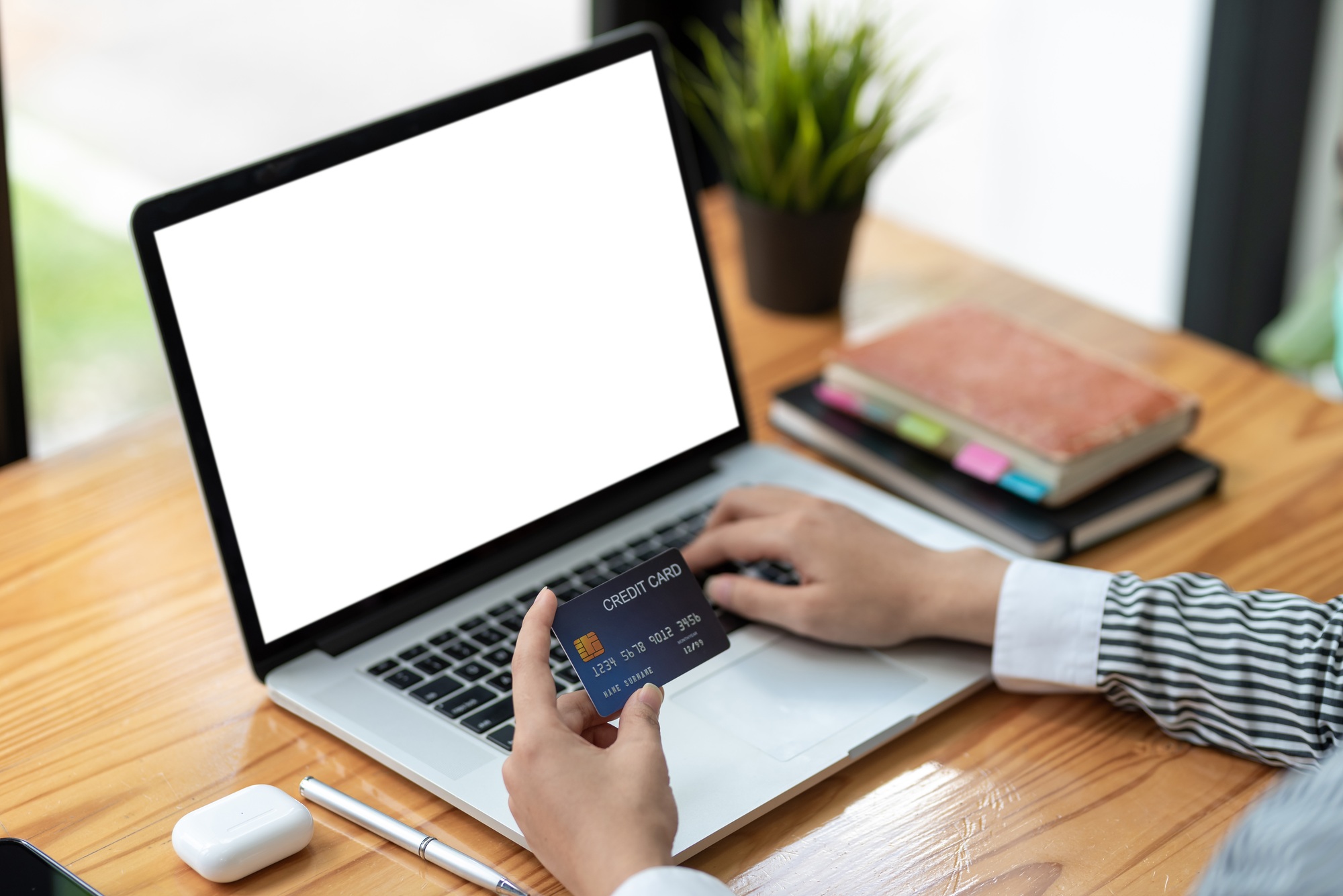 Close up of woman hands holding credit card and using laptop blank white screen. Online shopping con