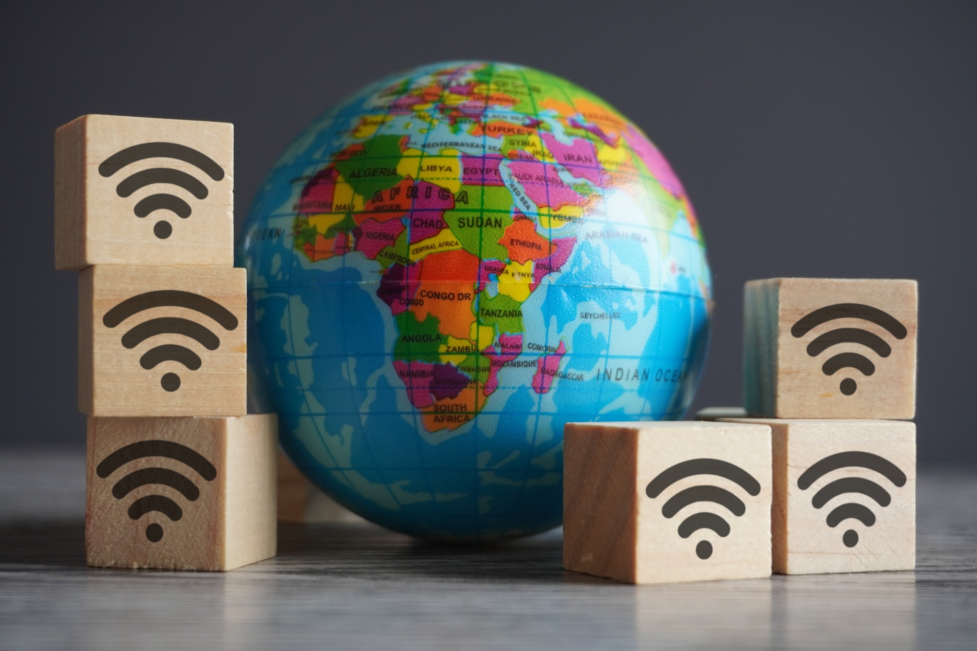 Closeup image of globe and wooden cubes with wifi icon.