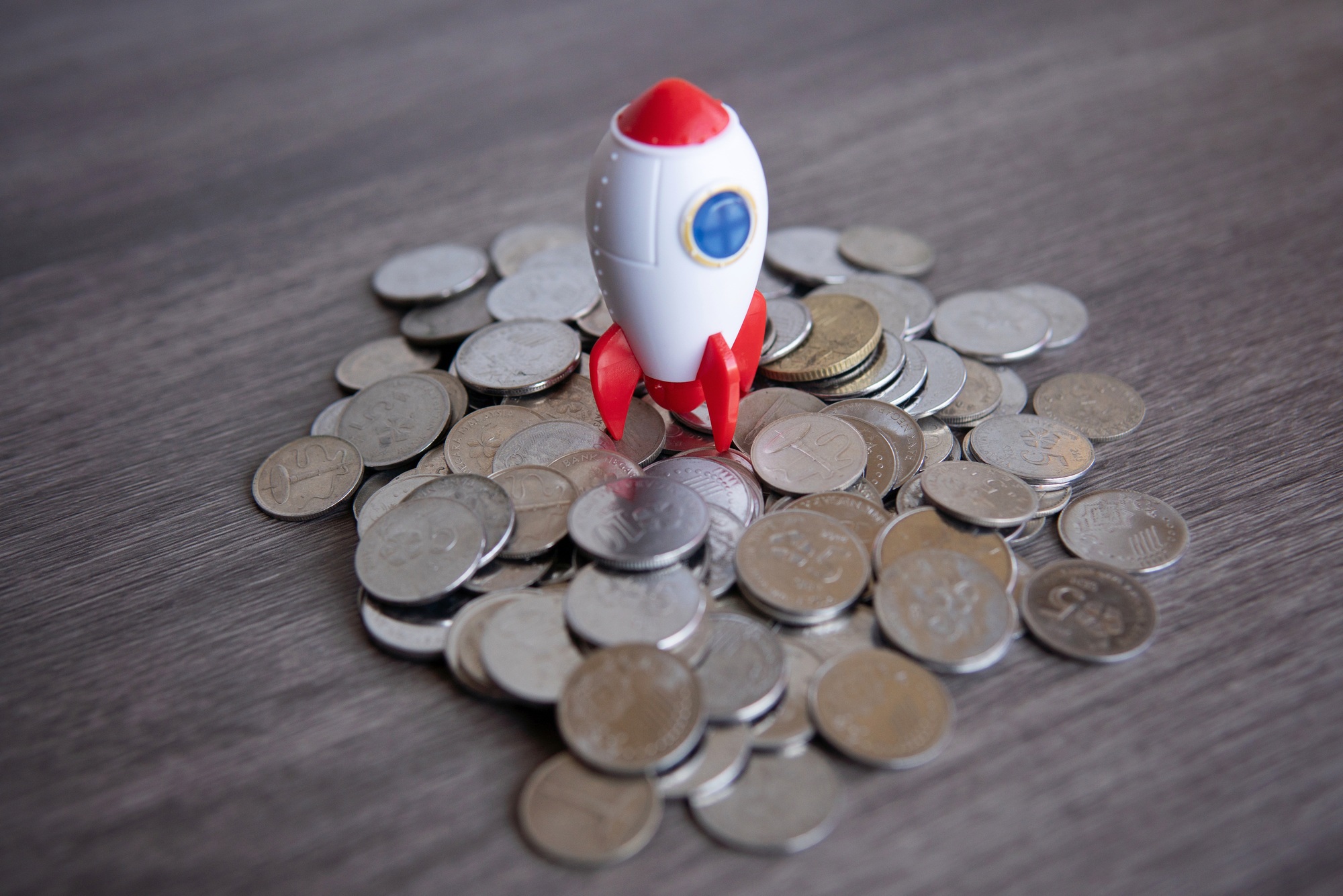 Closeup image of rocket spaceship and coins.