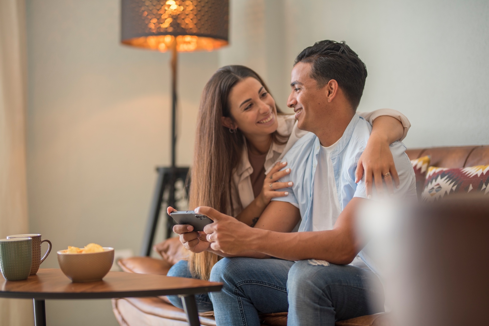 Couple in love resting on comfy couch having fun using smart phone apps, enjoy distant video call