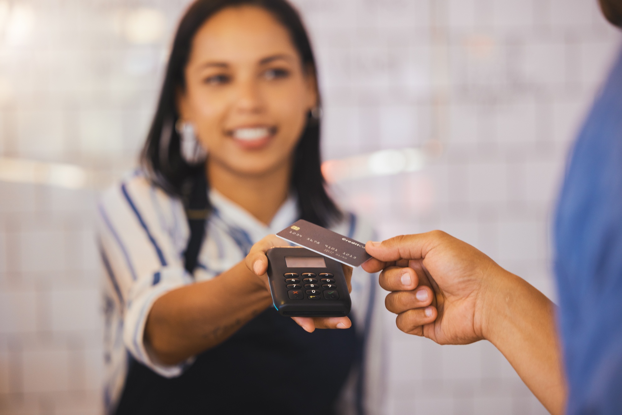 Credit card, payment and customer with an electronic reader  in the hand of a cashier to process a