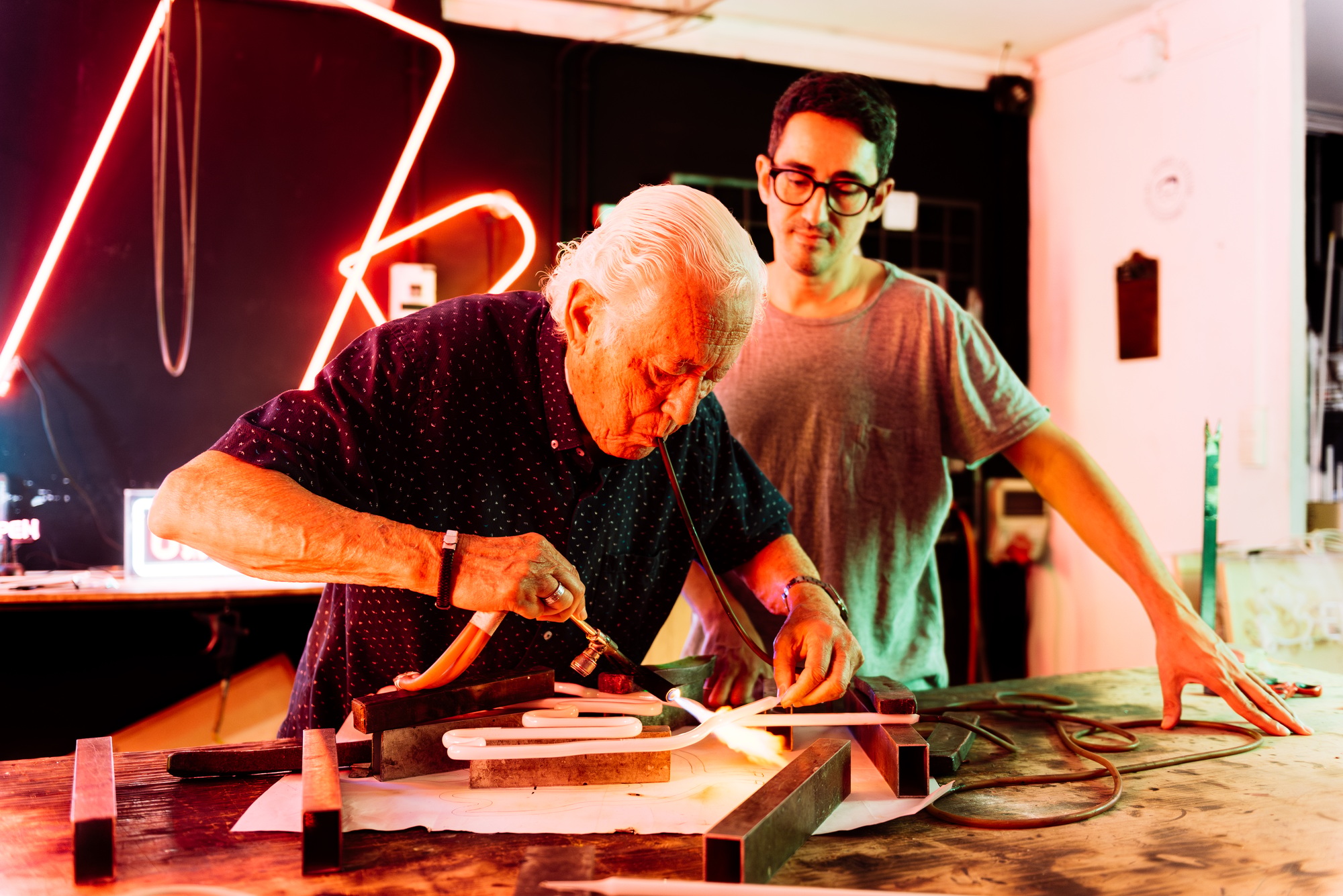 Experienced Neon Sign Maker Works With Apprentice in Workshop