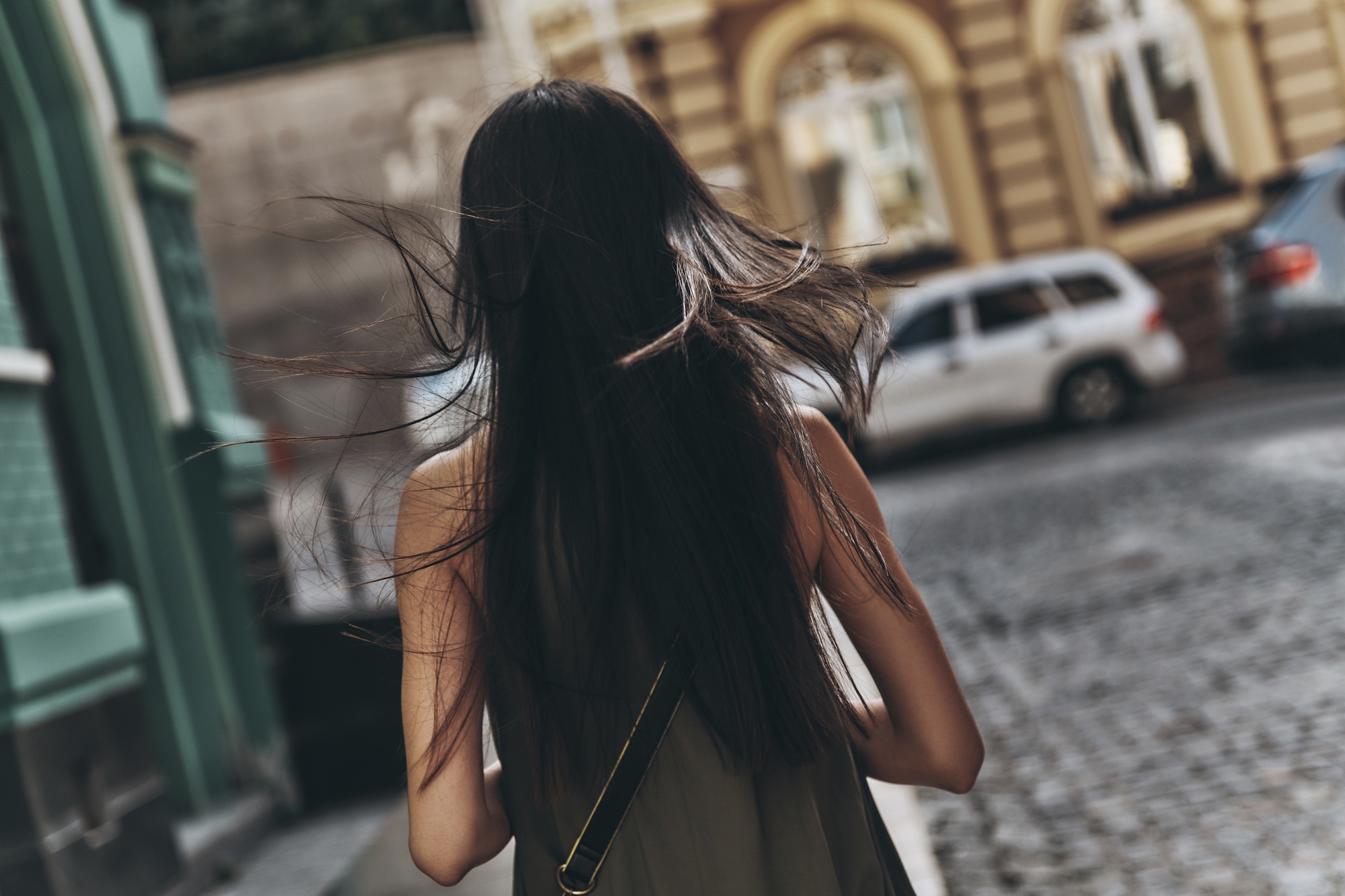 Follow your dream...  Rear view of young woman walking down the street while spending time outdoors