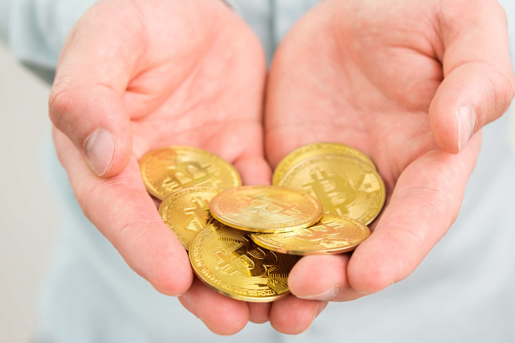Gold bitcoin coins in mans hand. Crypto currency payment concept
