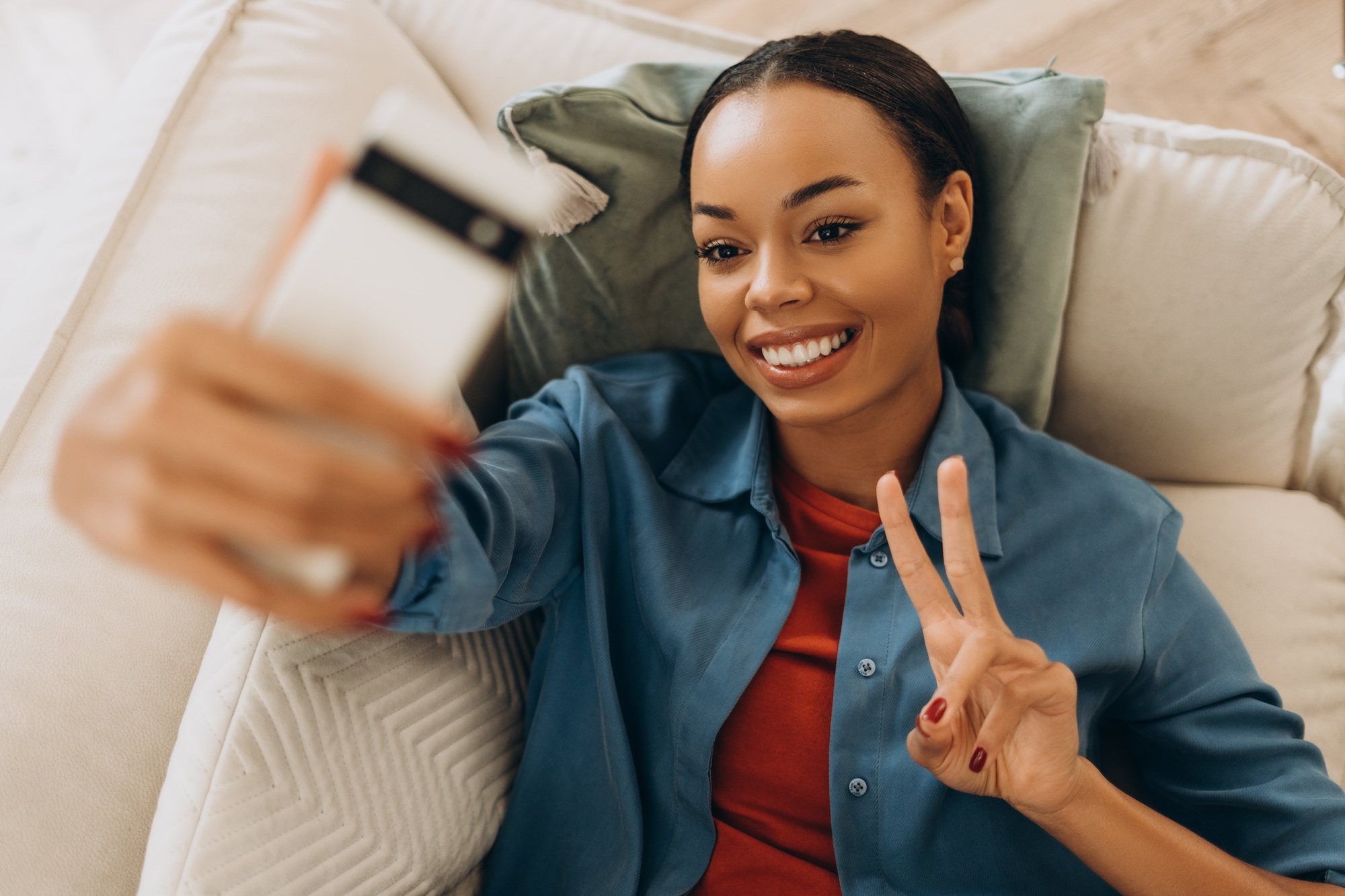 Happy African American woman holding mobile phone, using mobile app, influencer recoding video