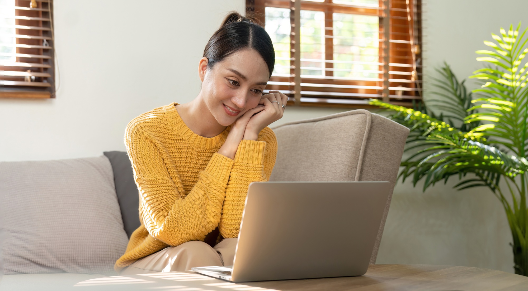 Happy Asian woman while using her laptop in the living room. work from home