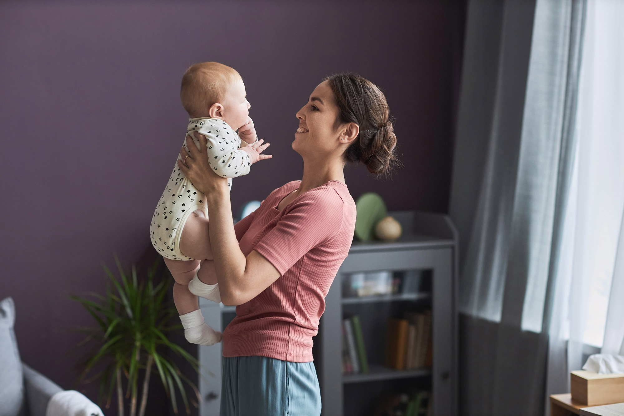 Happy Young Woman Holding Baby And Enjoying Motherhood