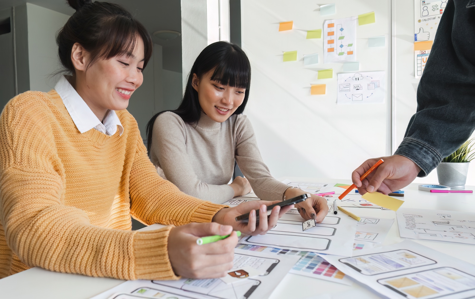 Image of a team of developers brainstorming UI and UX design ideas for a mobile app on a paper