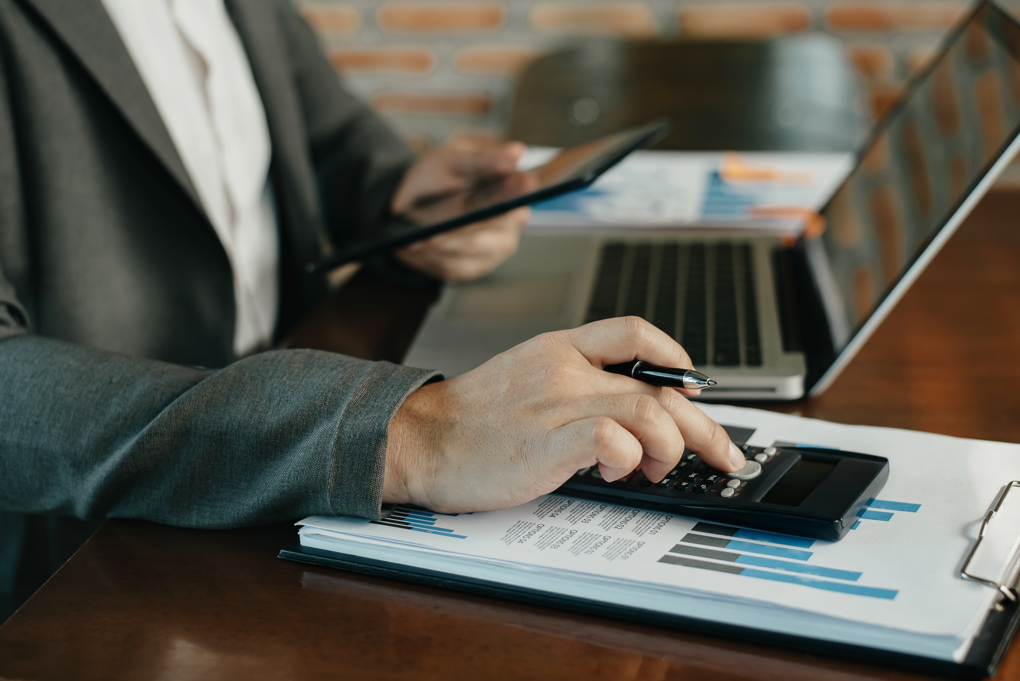 Investors are calculating on calculator investment costs and holding tablet and computer.