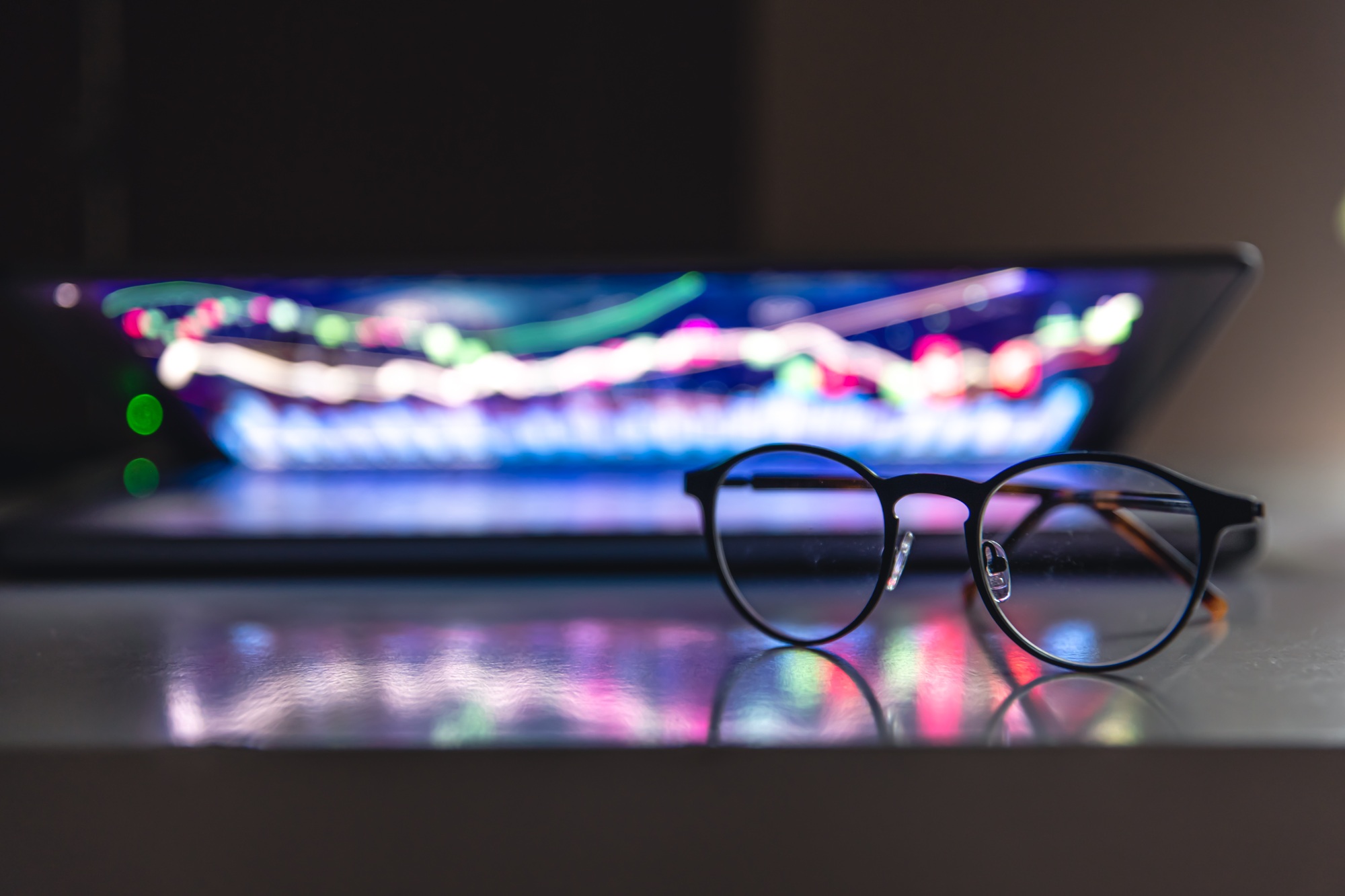 Laptop with graphs and statistics and glasses on the table.