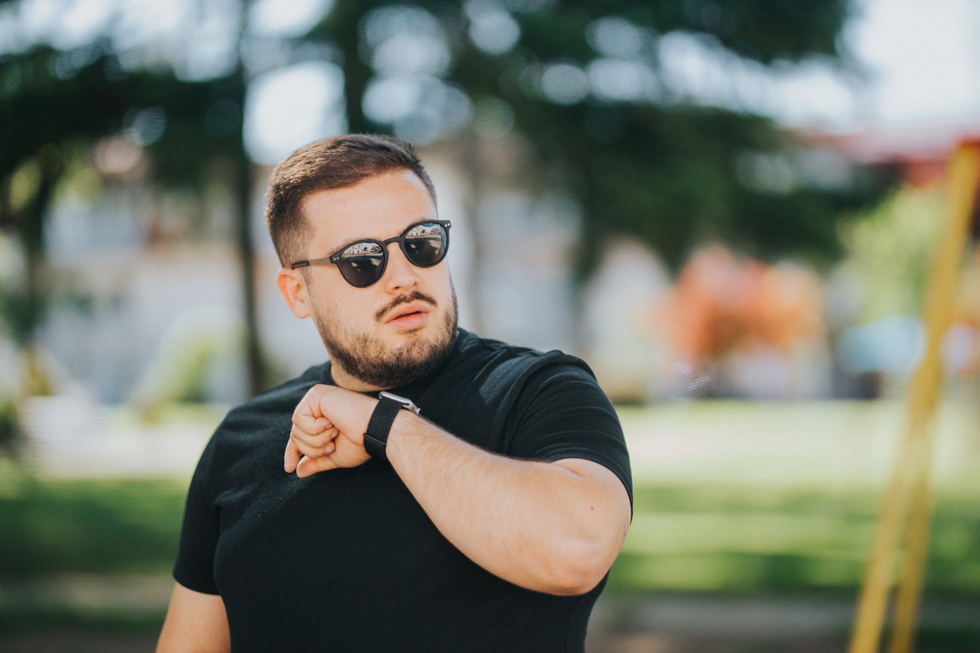 Male with a smartwatch is using a voice command recorder or taking a call while resting in the park