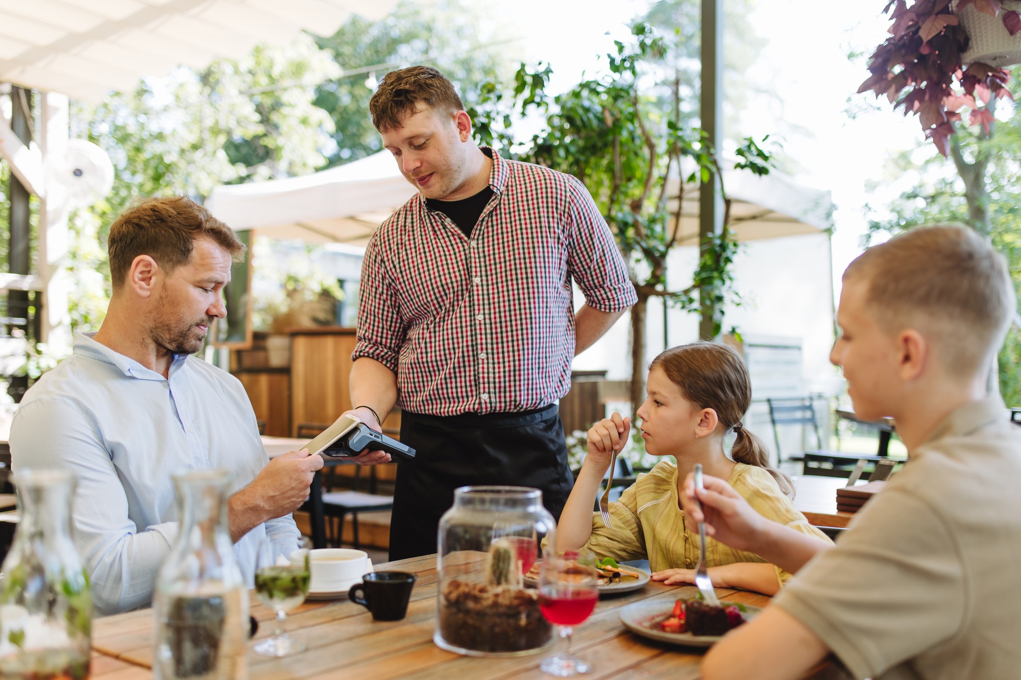 Man paying for lunch in restaurant, paying by card. Holding card near terminal card reader.