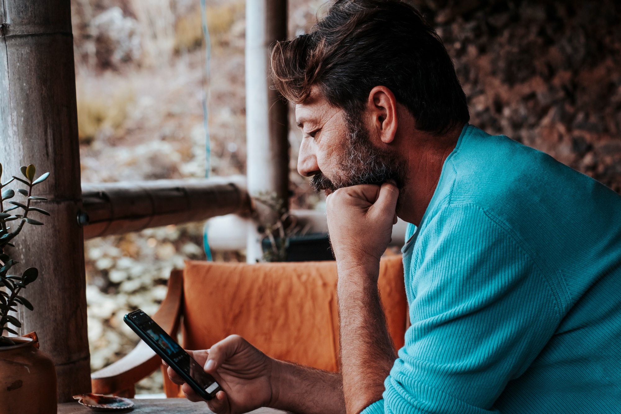 Mature man using and looking mobile phone worried at home. Modern adult people with device