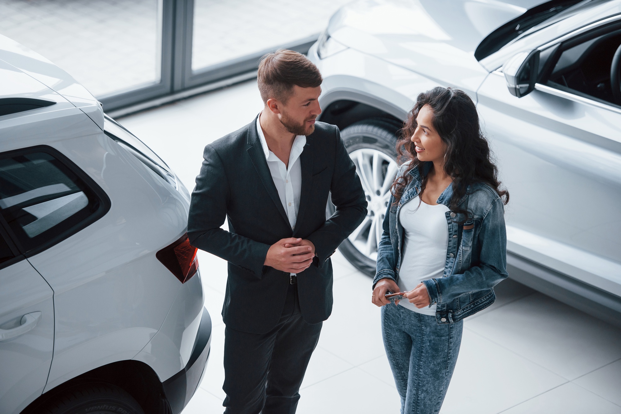 Need some advices. Female customer and modern stylish bearded businessman in the automobile saloon