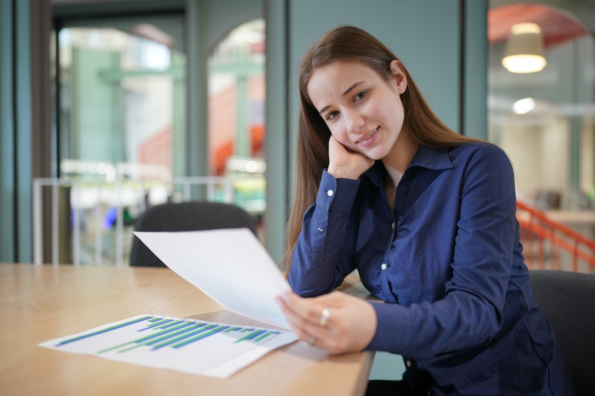 oung concentrated businesswoman holding pen filling document or tax form, making notes on paper