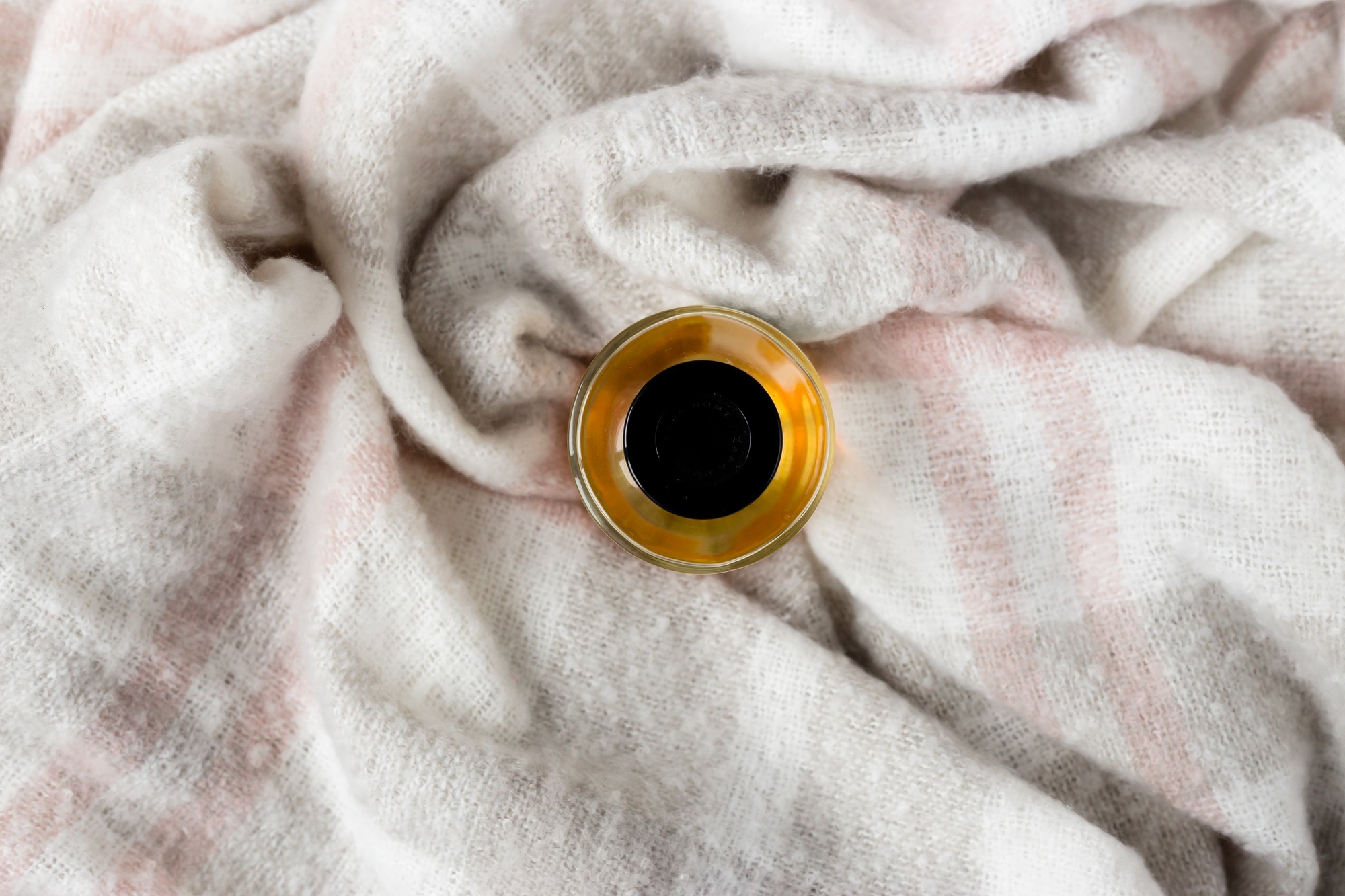 Perfume jar on crumpled gray wool blanket. Soft and warm fabric crumpled in folds. Texture