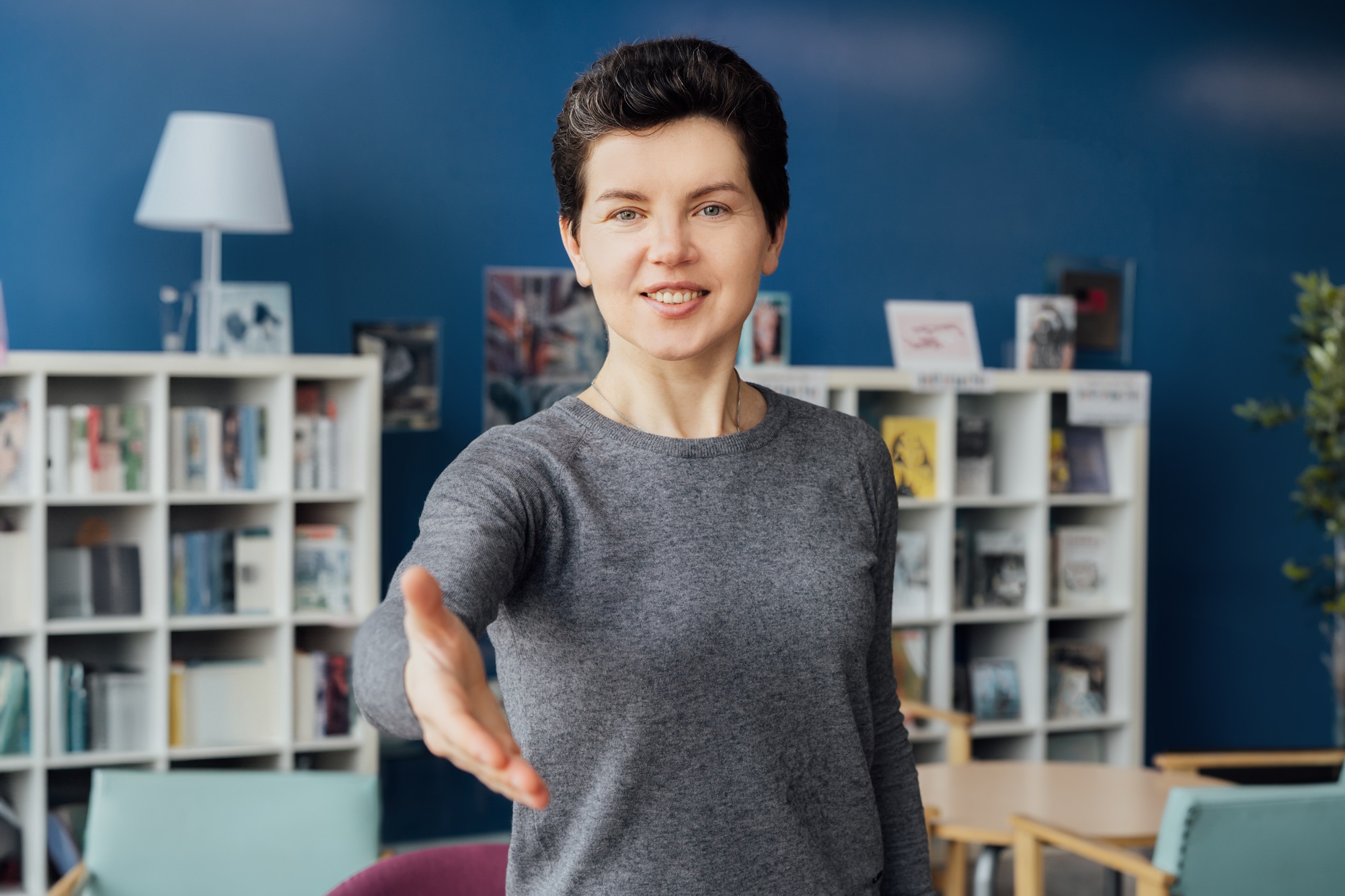 Polite friendly middle aged neutral gender hr manager recruiter stretching hand to spectator