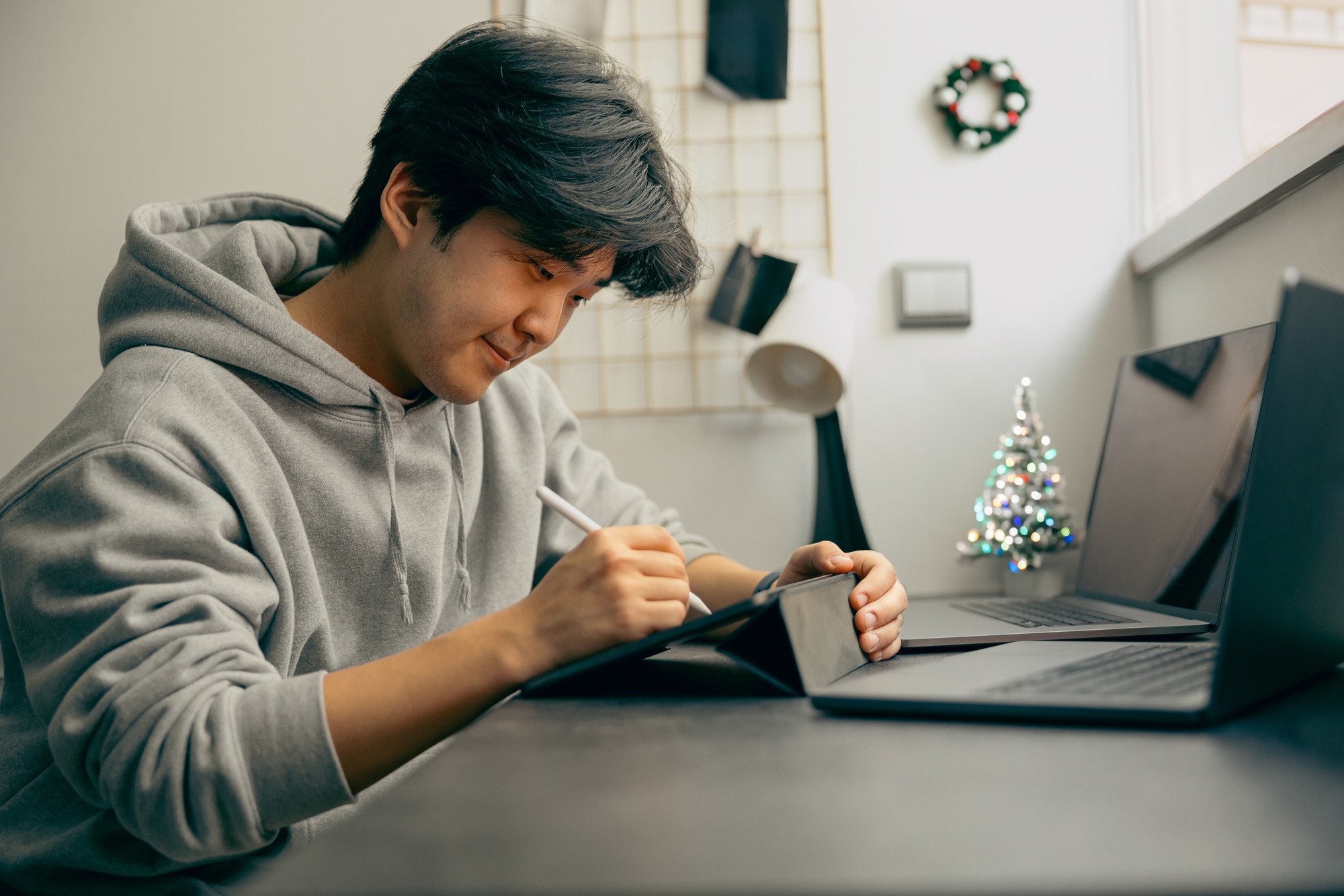 Professional smiling male graphic designer use digital tablet and laptop for working from home