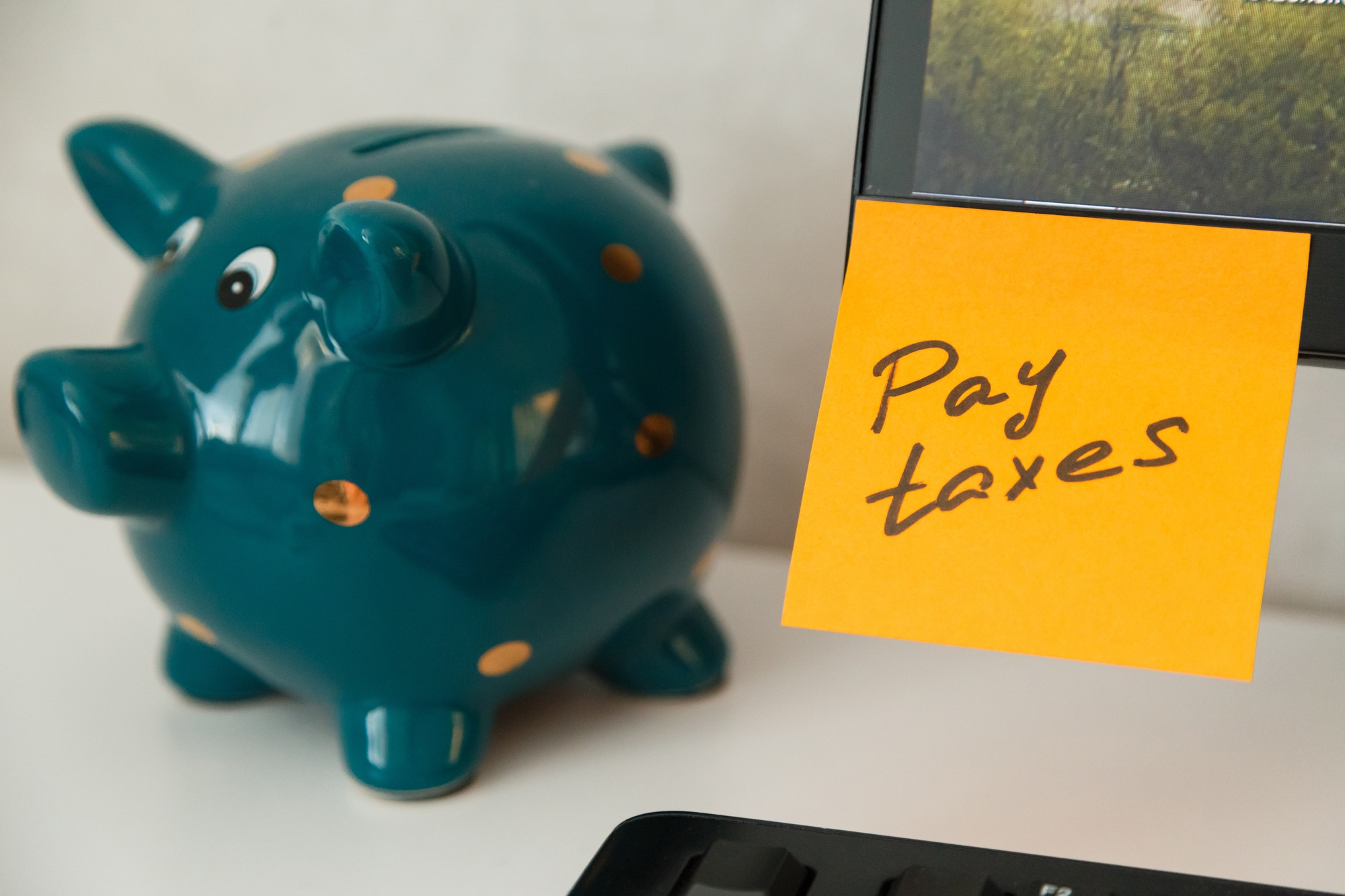 Reminder pay taxes sticked on monitor at freelancer's workplace