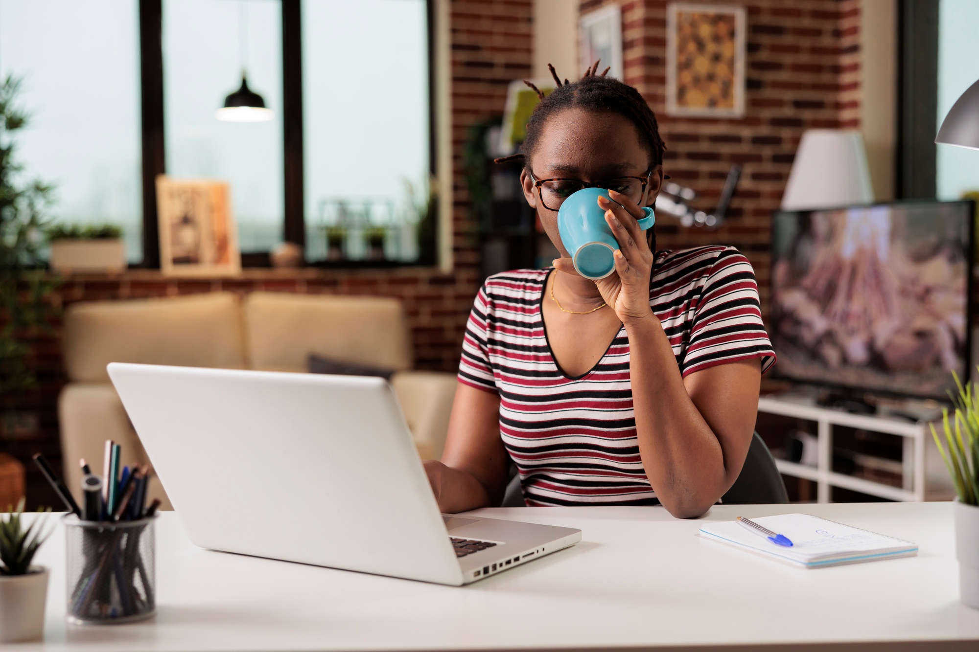 Remote student watching educational tutorial on laptop, drinking coffee