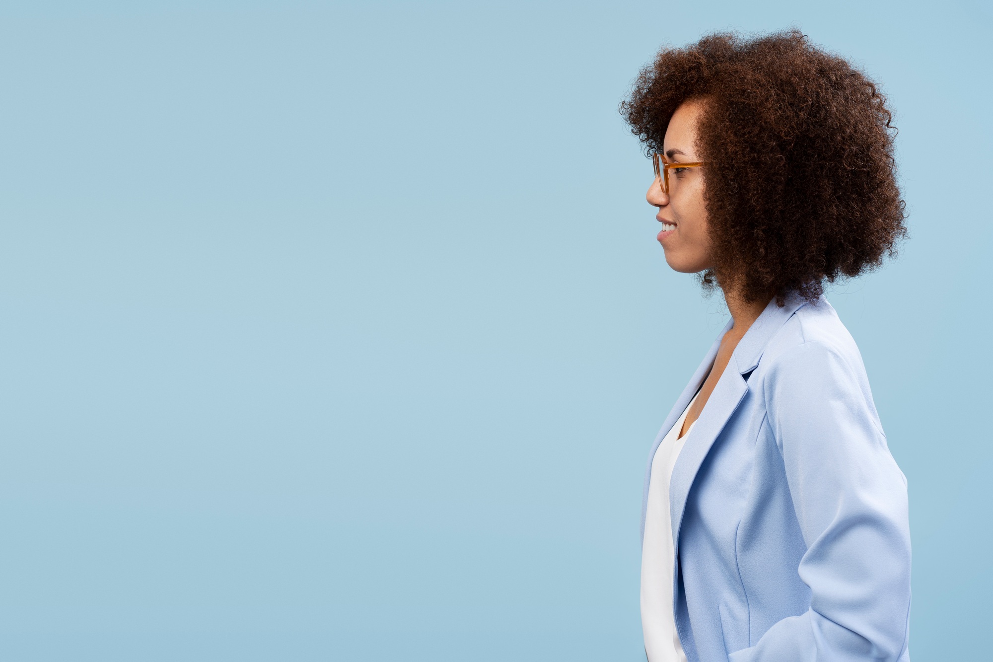 Side portrait of African American woman, looking at copy ad space, isolated on blue color background