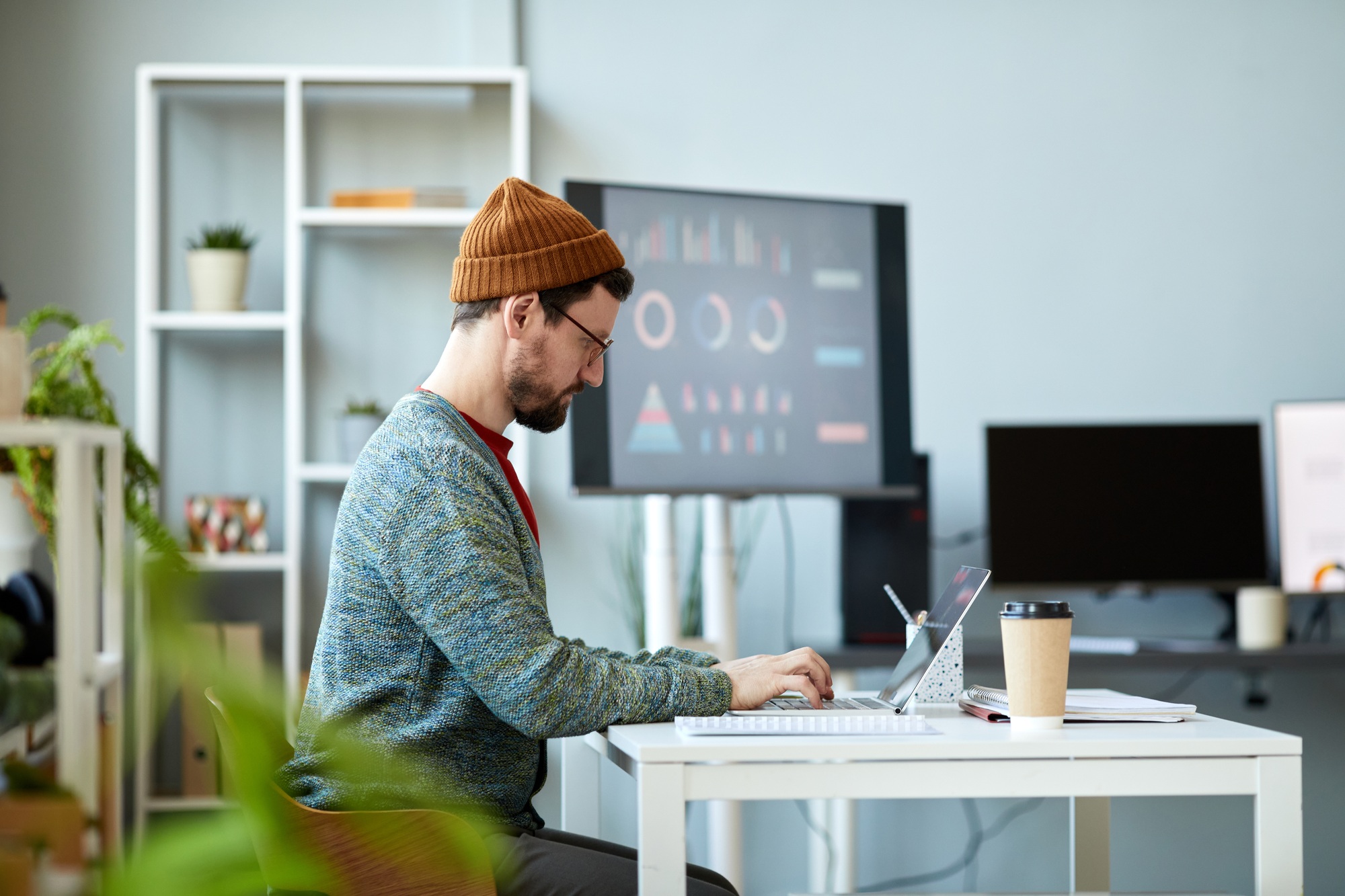 Side view of young serious businessman concentrating on network in office