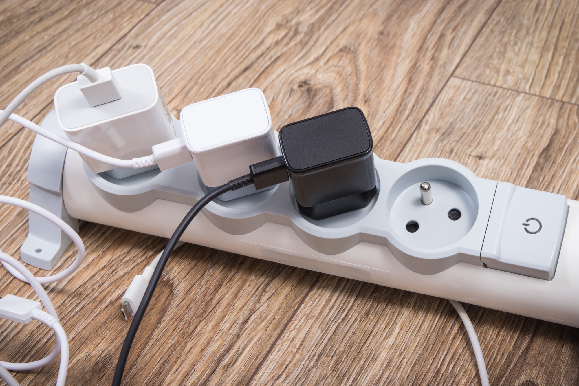Smartphone chargers connected to electrical power strip. Various devices charging