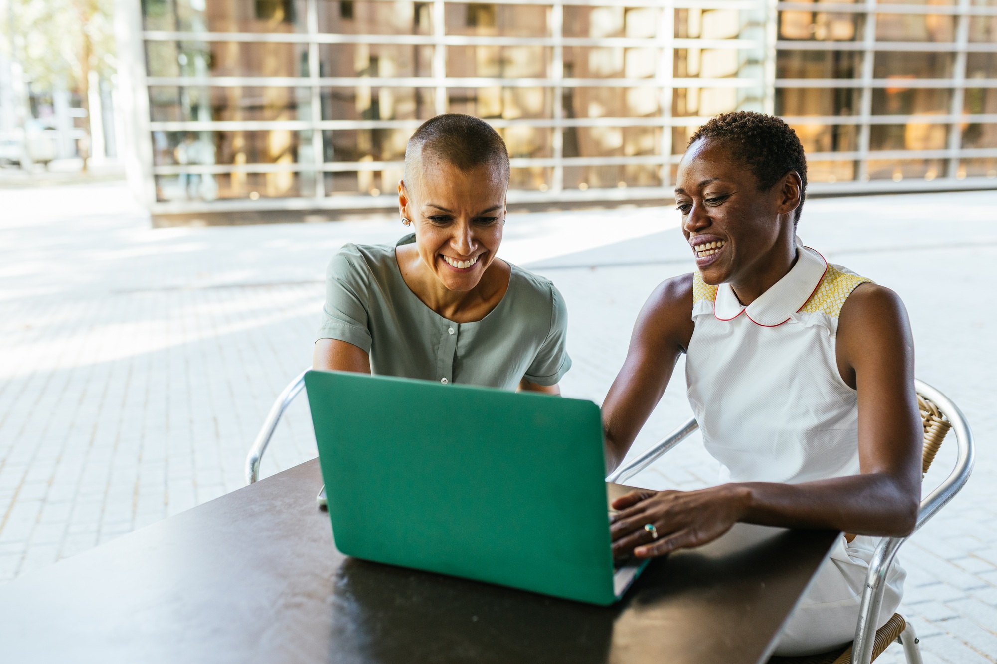 Smiling Businesswomen Working on Laptop at Bar Terrace