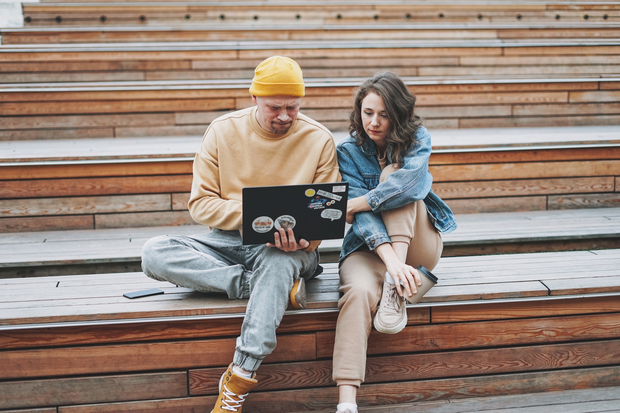 Stylish young couple freelancers working on laptop at city park