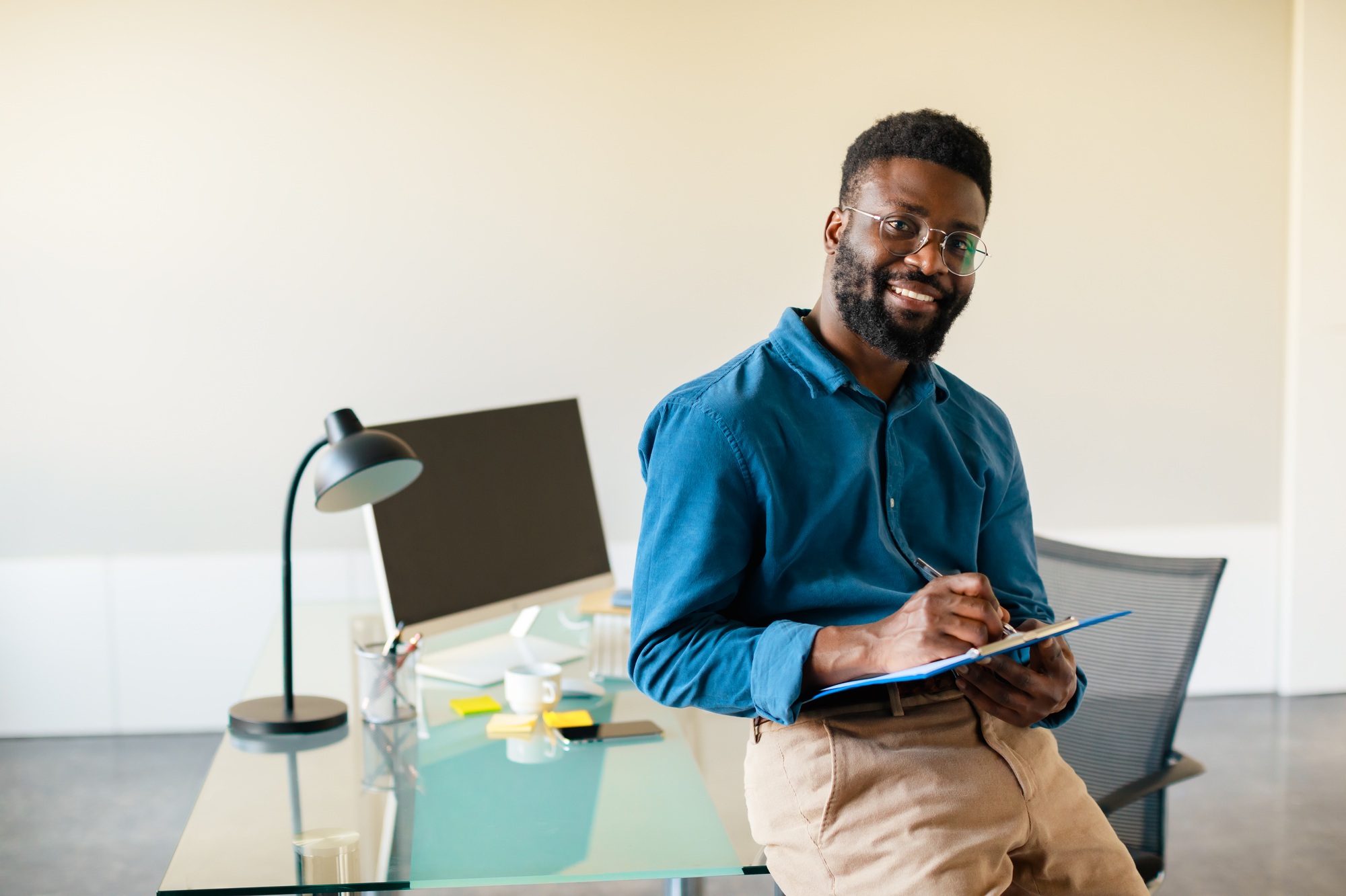 Successful entrepreneurship concept. Excited black businessman holding clipboard with documents and