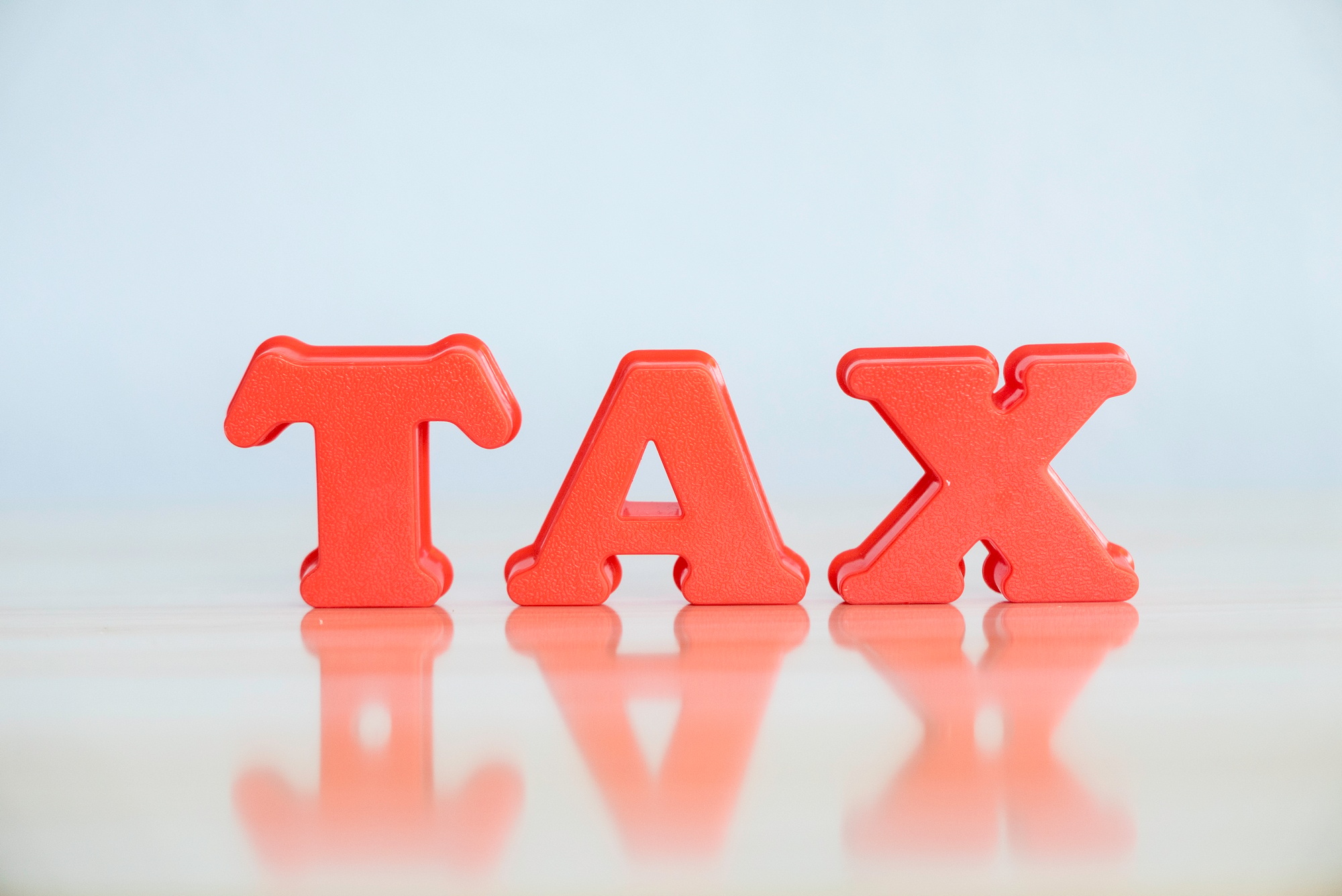 Tax concept. Red alphabet of word tax on wooden background.