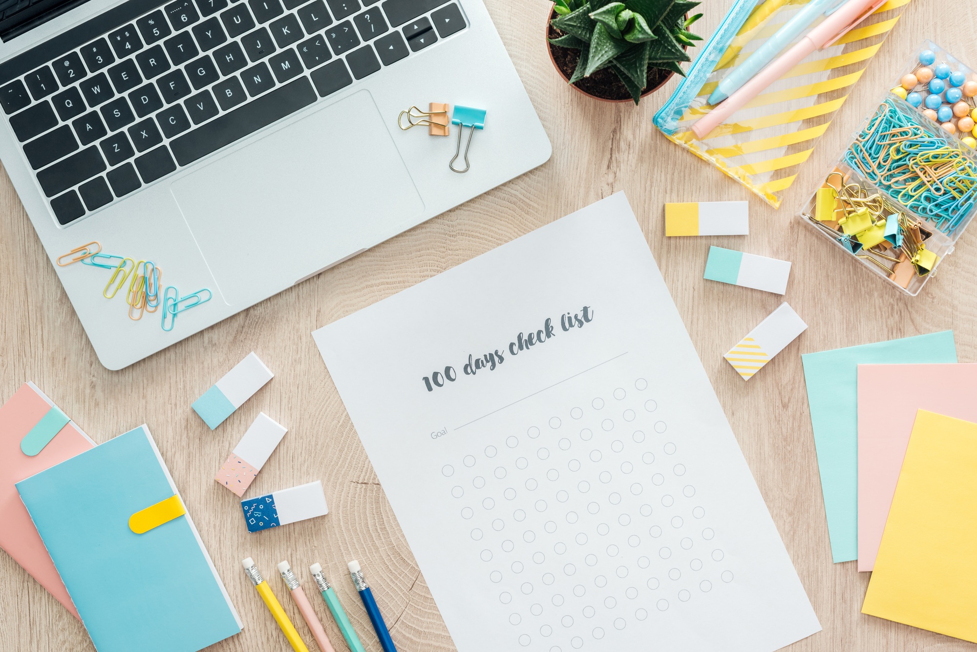 top view of 100 days check list, stationery and laptop on wooden table