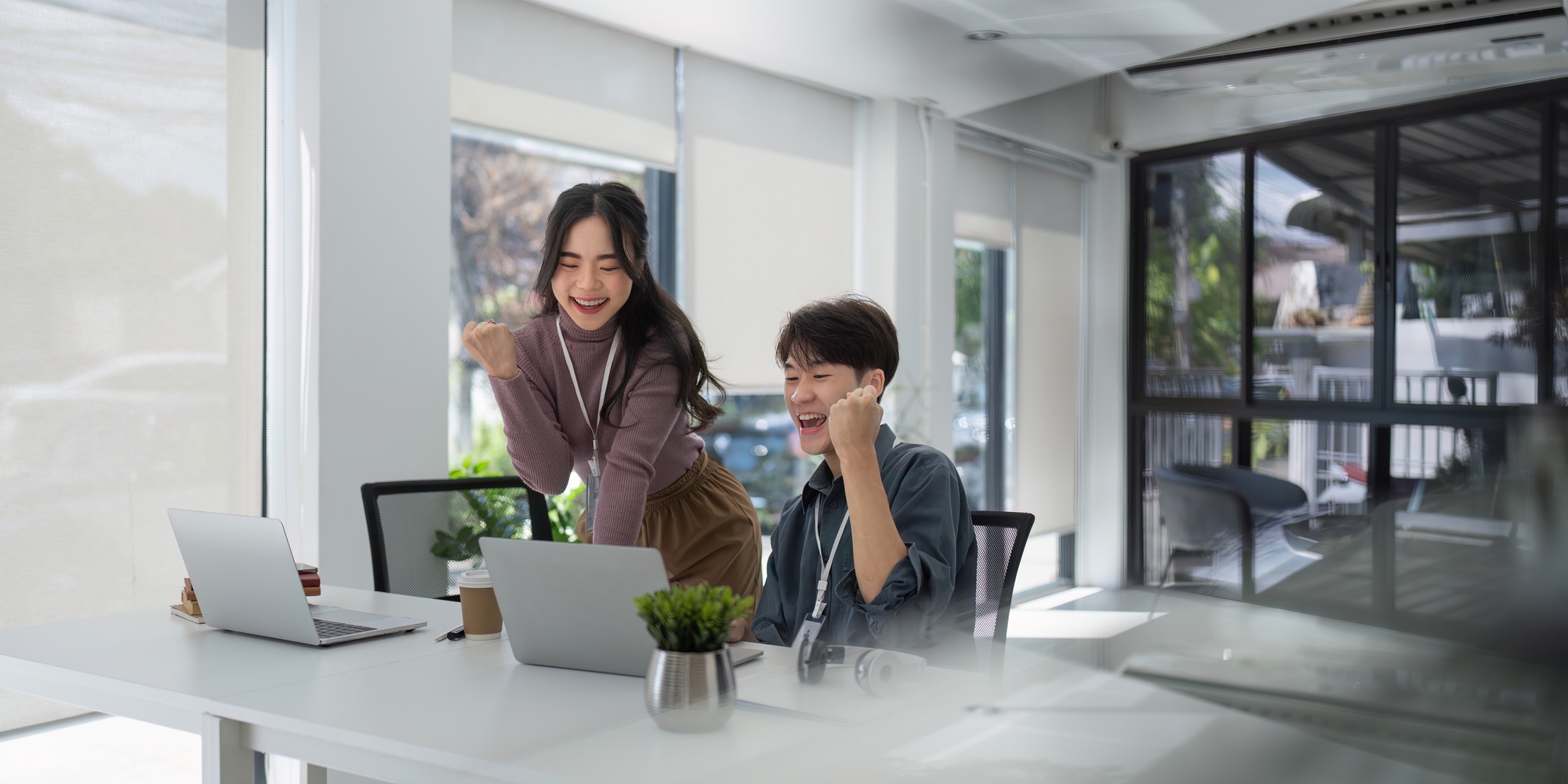 Two asian business raises her hands up rejoices in increasing profits in business. Business woman