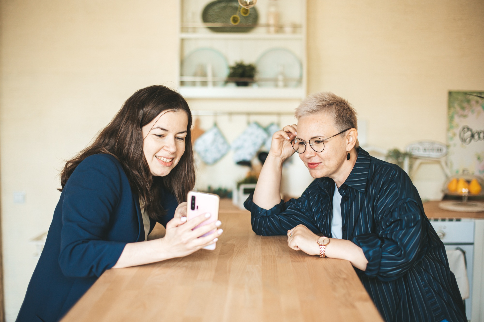 Two female business ladies discussing social media content at home.