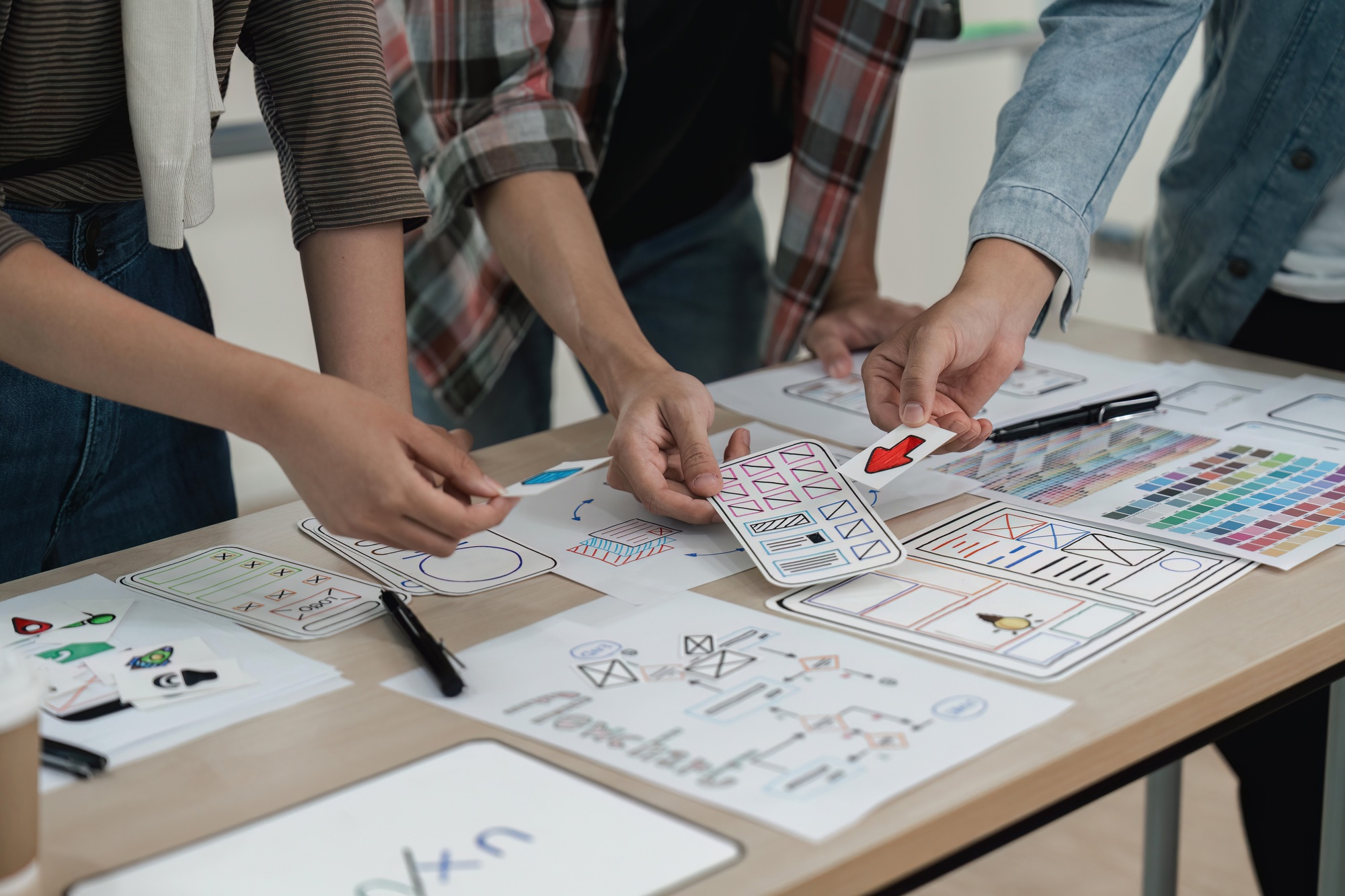 UX developer and UI designer brainstorming about app interface wireframe design on table with