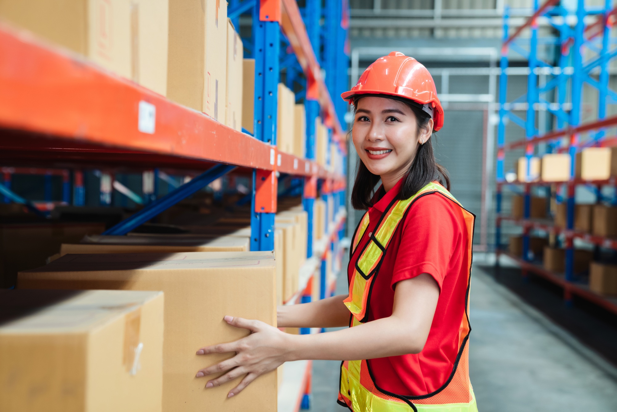 Warehouse female worker holding box package and moving boxes on the shelf.