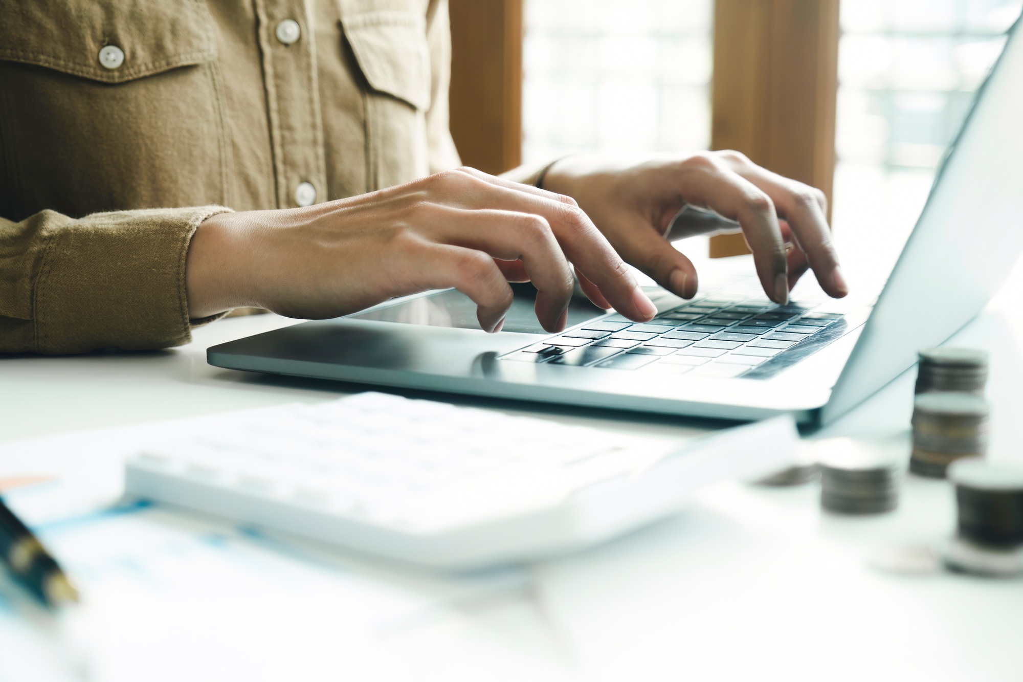 Woman accountant working on laptop computer while counting taxes online.