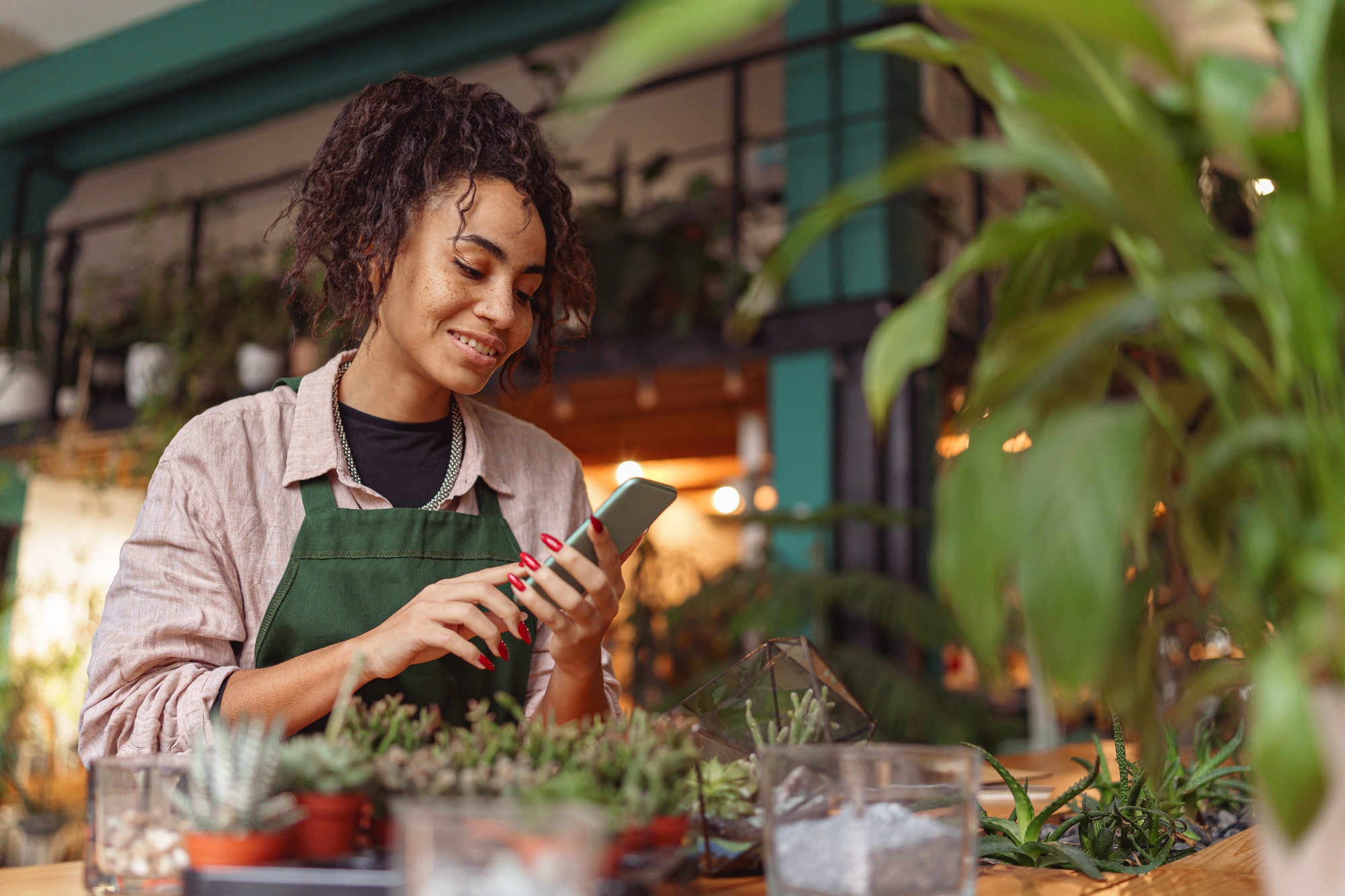 Woman florist use mobile phone during working day in floral design studio