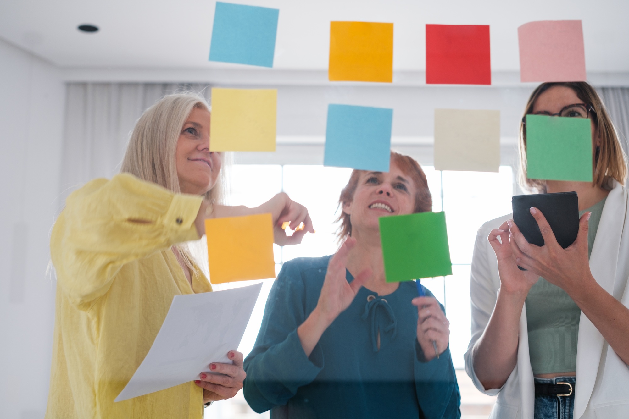 Women writing down ideas and innovations on post-it notes to make investments and generate benefits.