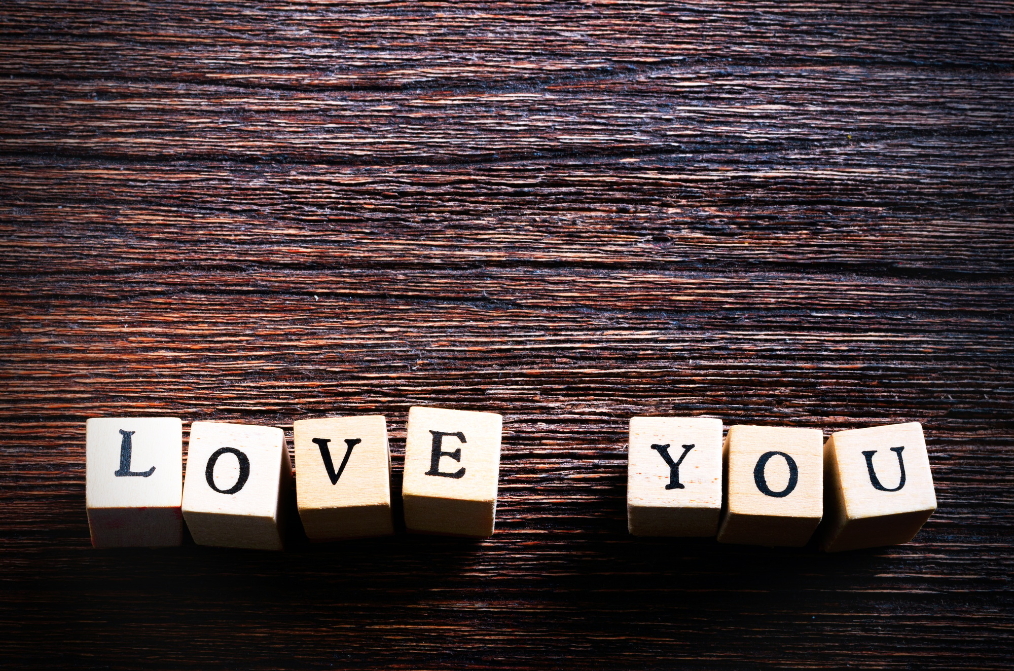 Wood cubes with inscription LOVE YOU on wooden background. Free space for your text
