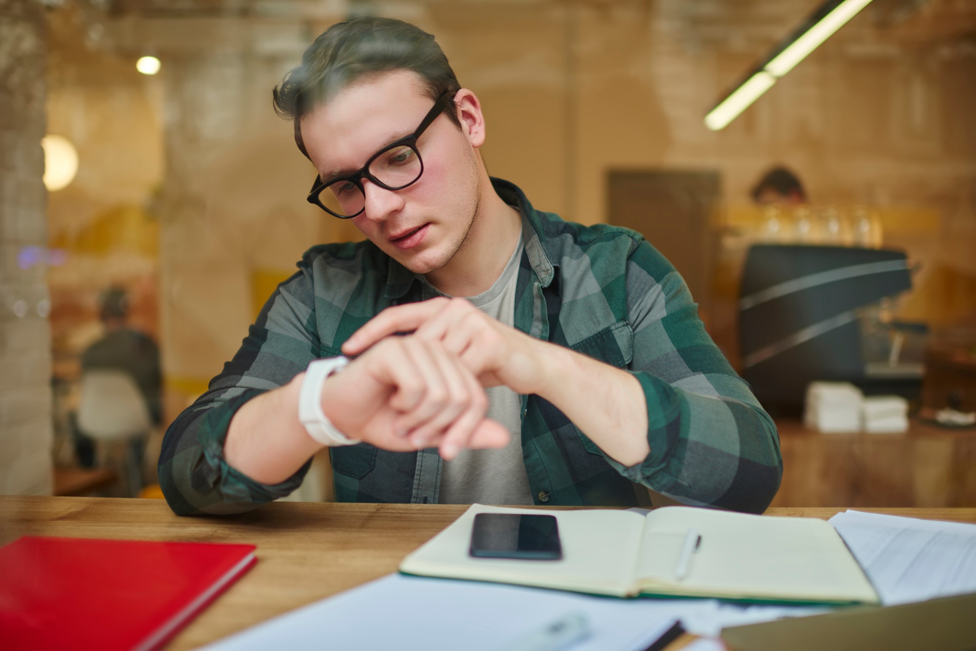 Young smart guy checking time on smartwatch.