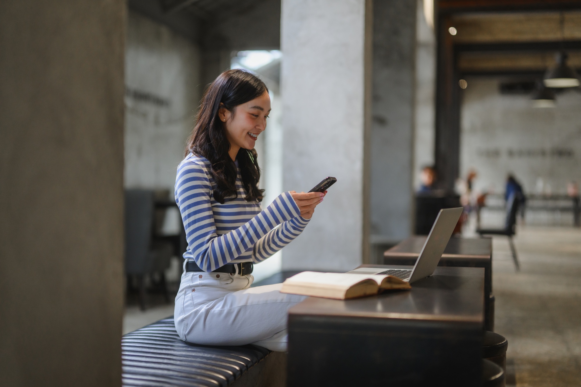 Young student using smartphone and studying in modern library
